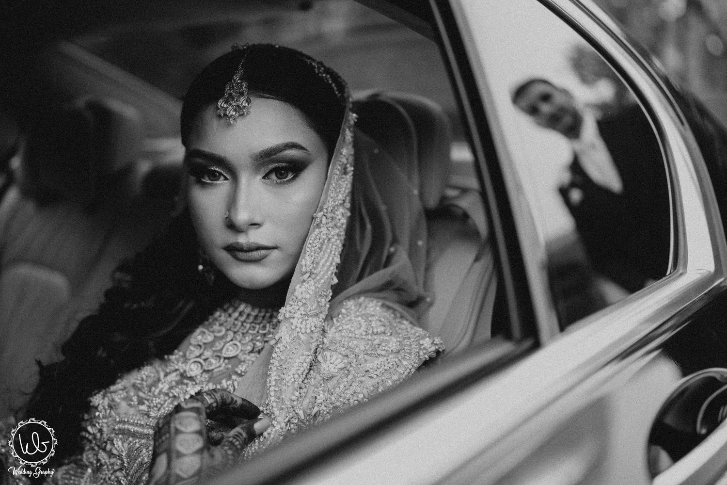 Black and white photos of a bride in traditional attire sitting in a luxury car.
