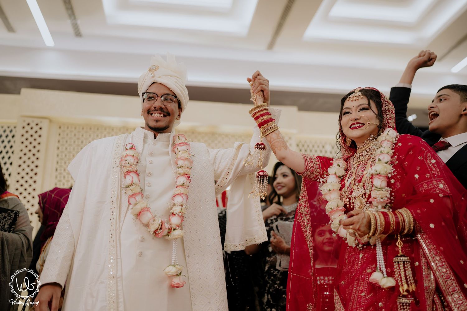 Wedding celebration with couple in traditional Indian attire during indoor ceremony.