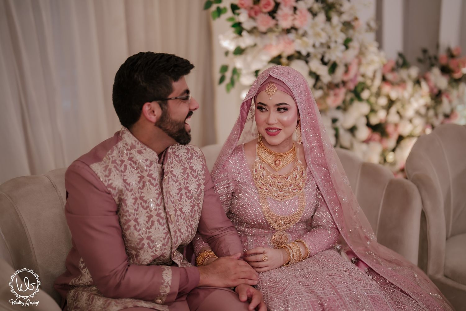 A couple in traditional South Asian wedding attire sharing intimate moments during their celebration ceremony.