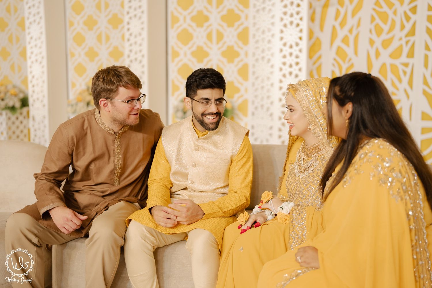 A group wearing traditional yellow and brown Indian attire poses together during a festive celebration.