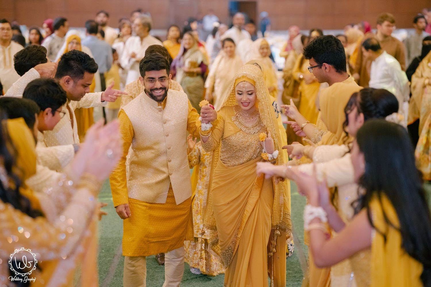 Wedding celebration with guests dancing and enjoying festivities in a decorated venue with yellow and pink decor.