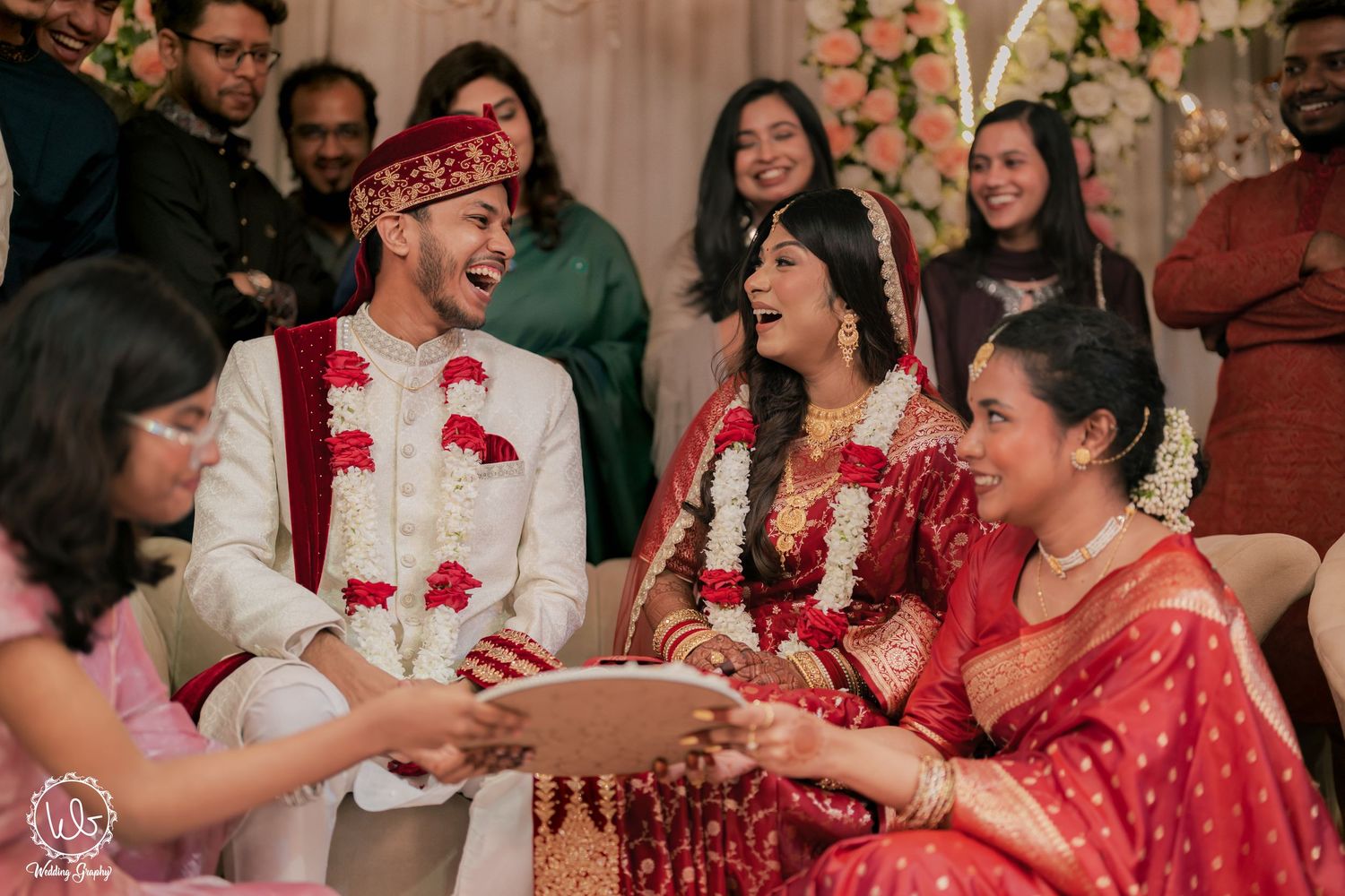 Joyful wedding celebration with guests in traditional red and white attire.