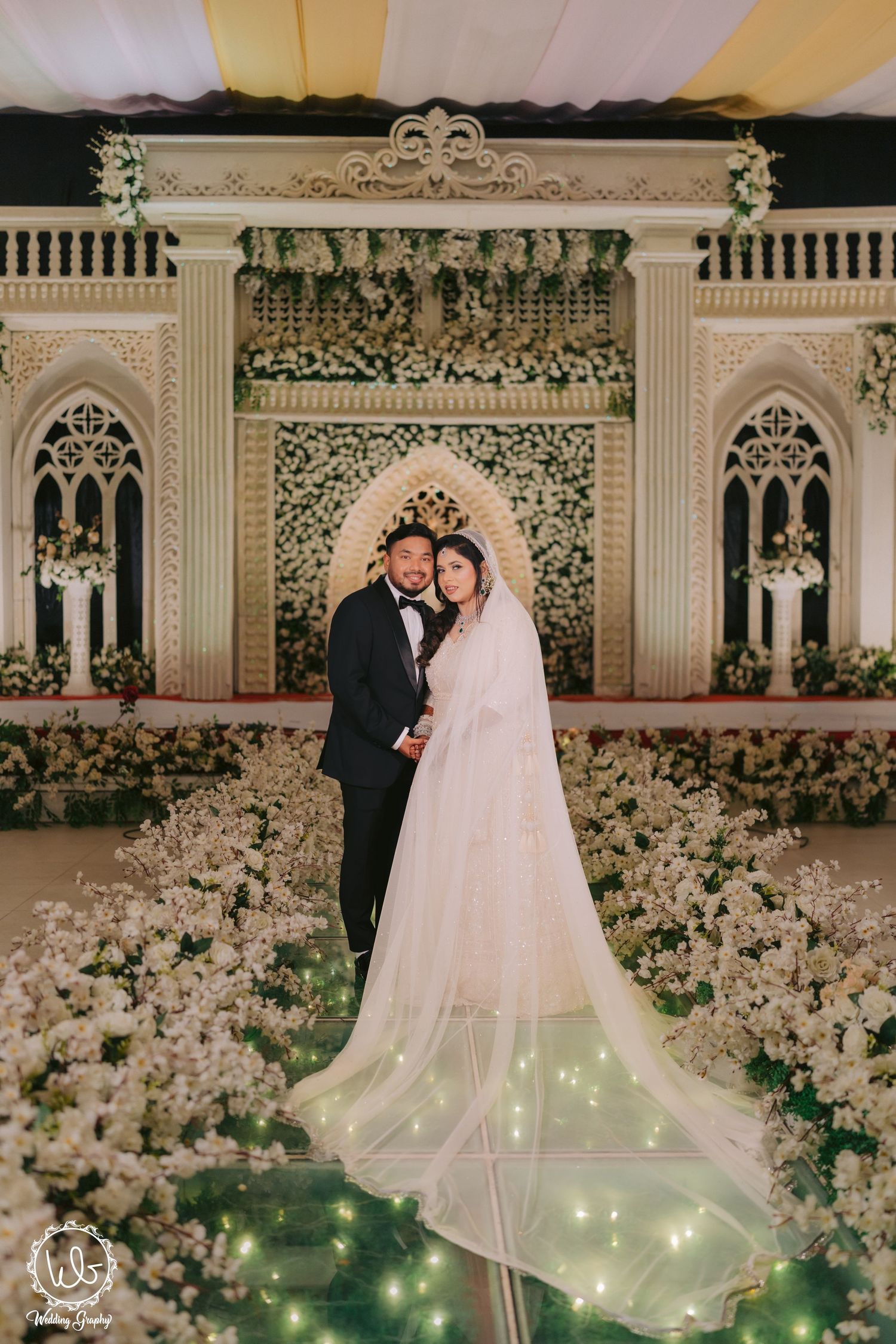 Elegant wedding ceremony setup with white floral arrangements and twinkling lights creating a romantic atmosphere.
