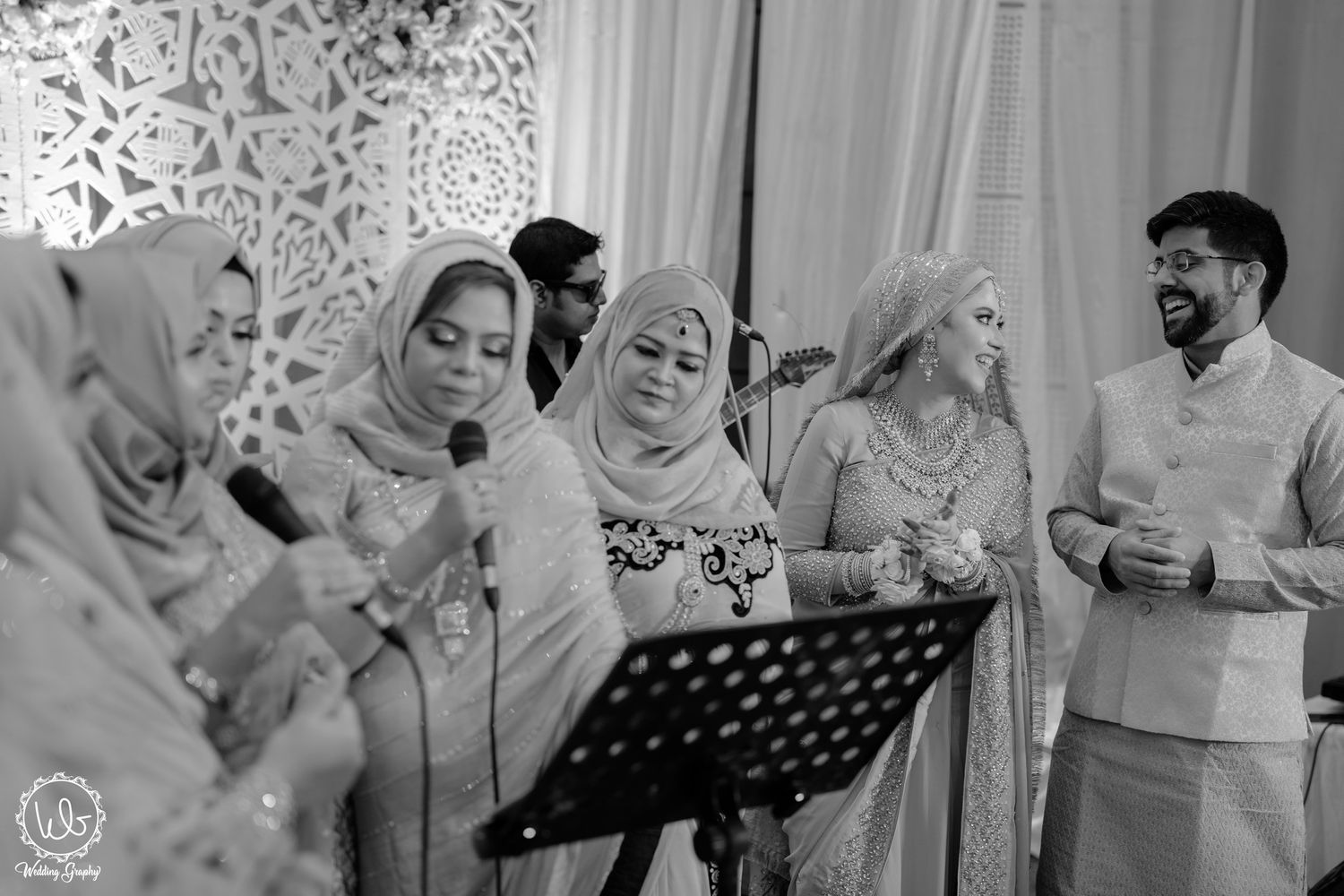 Musicians in traditional attire perform together while reading from music stands during a cultural event.