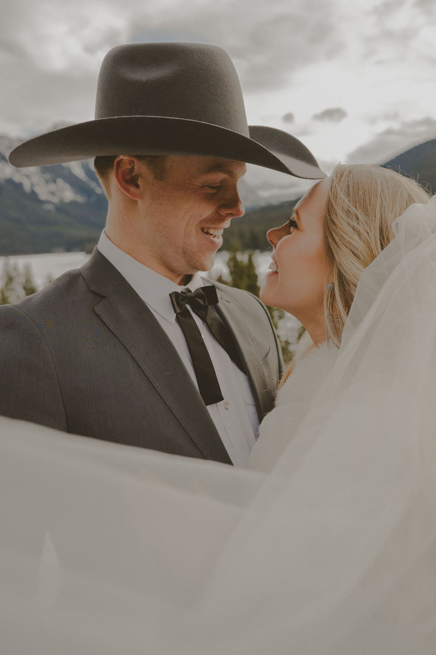 A romantic wedding couple embraces under cloudy skies in a series of intimate portraits wearing traditional formal attire.