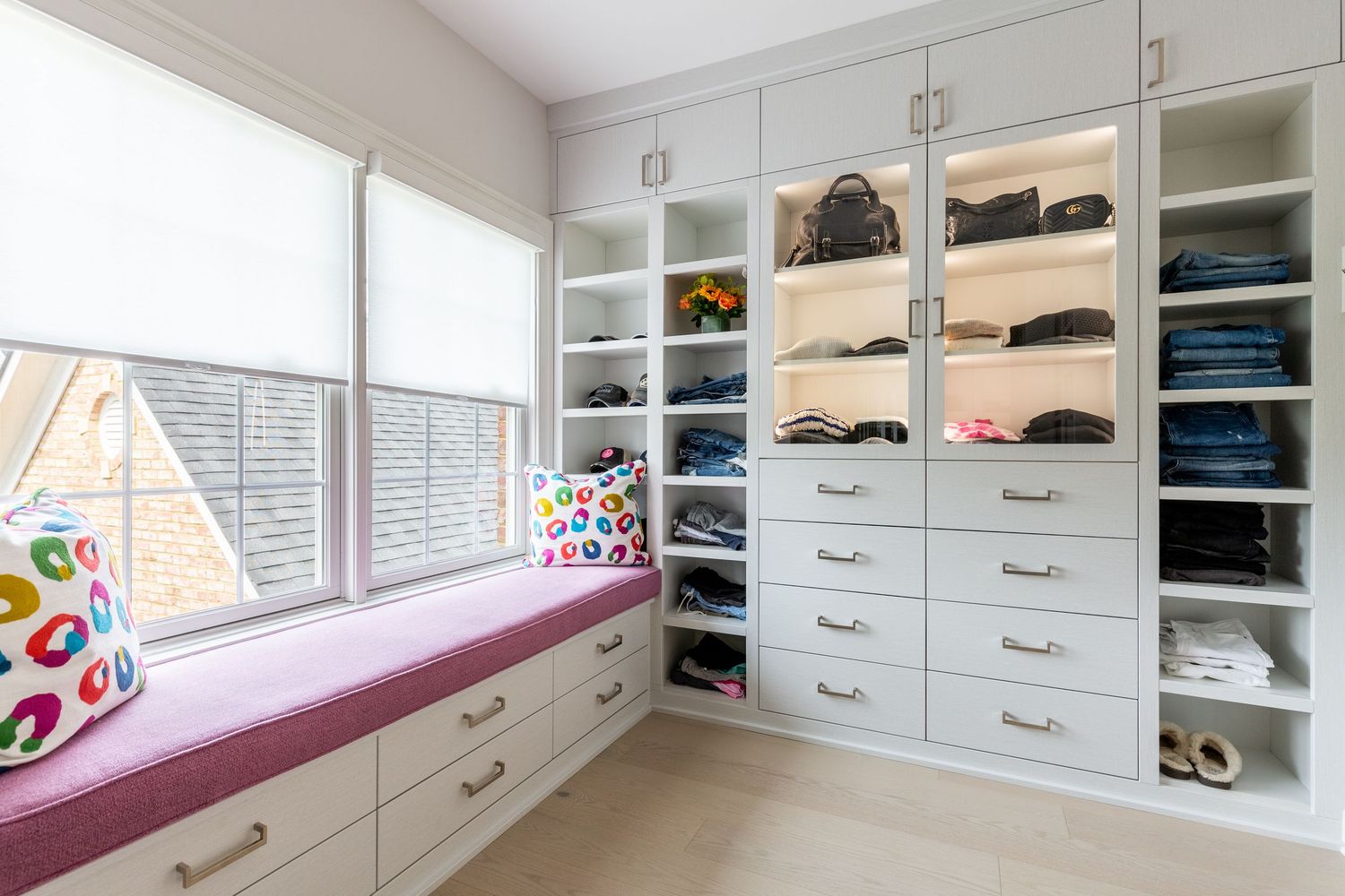 Custom walk-in closet with white built-in shelving and bench seating.