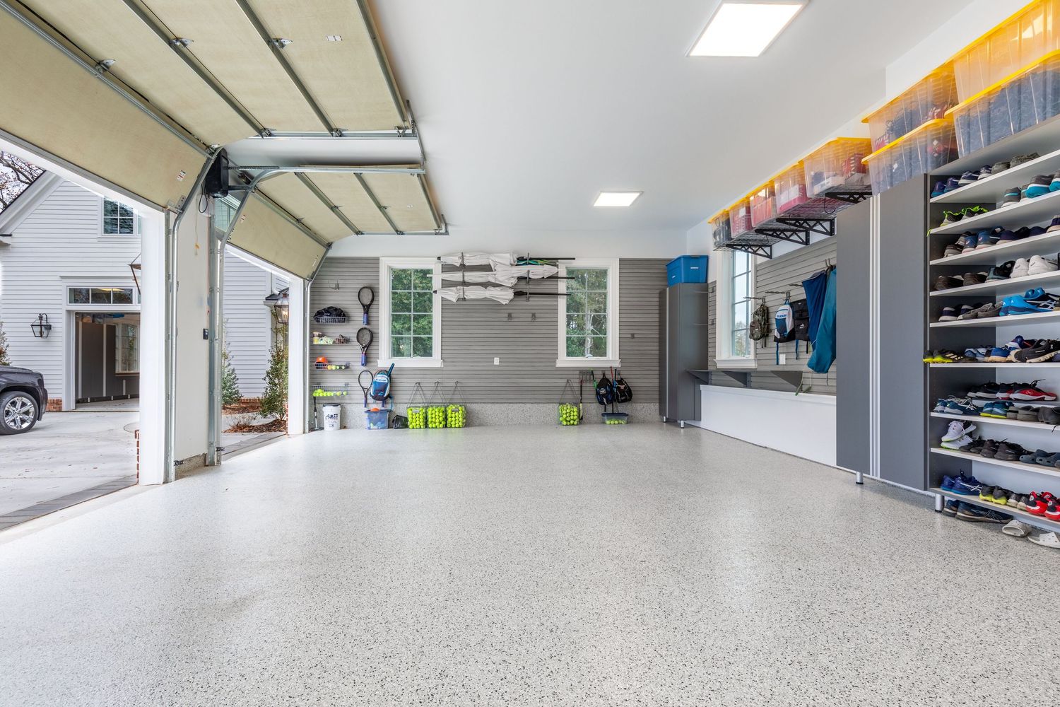 Clean and organized garage interior with epoxy flooring, built-in storage cabinets, and bright LED lighting.