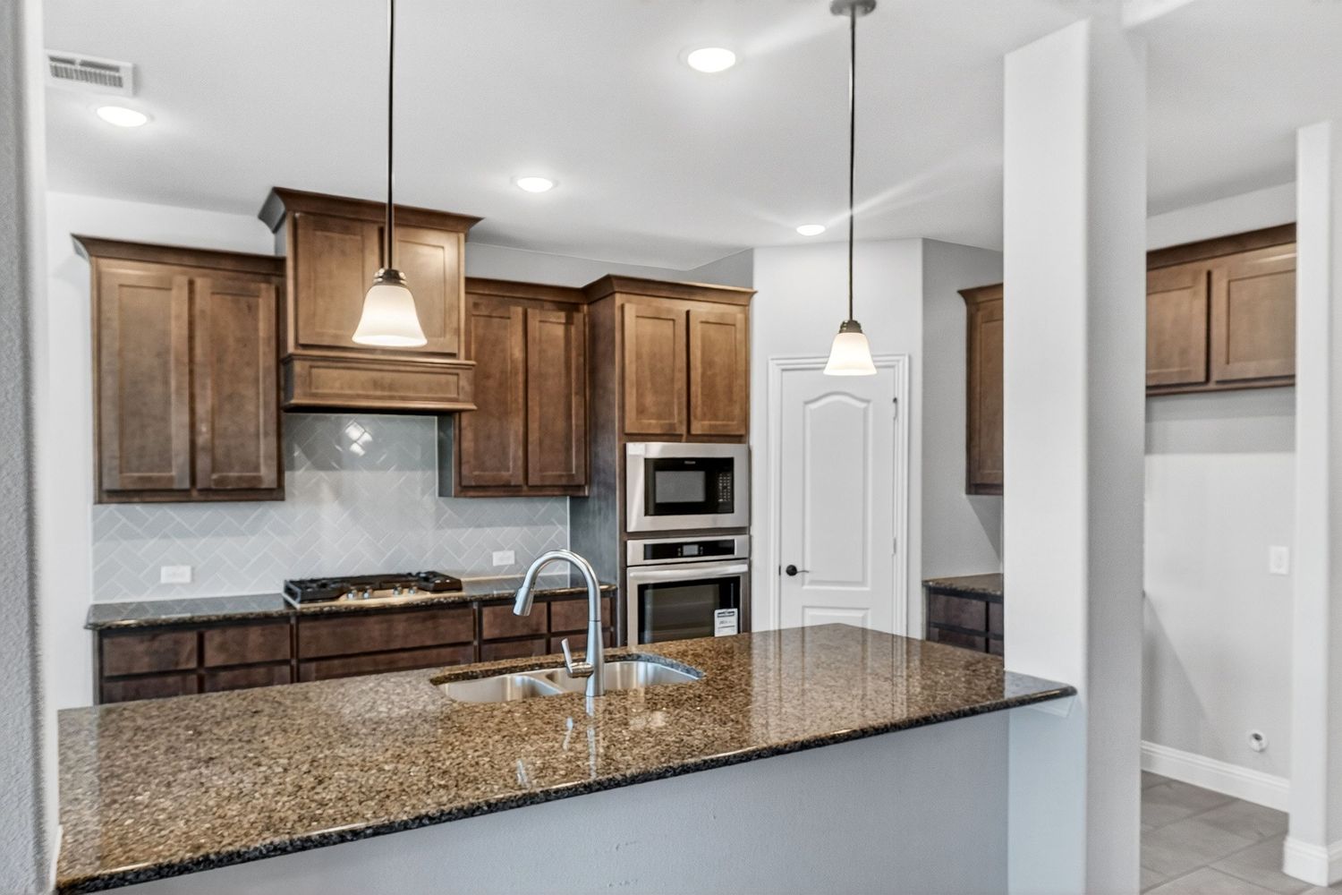 Spacious open-concept kitchen with granite countertops, dark wood cabinets, and stainless steel appliances.