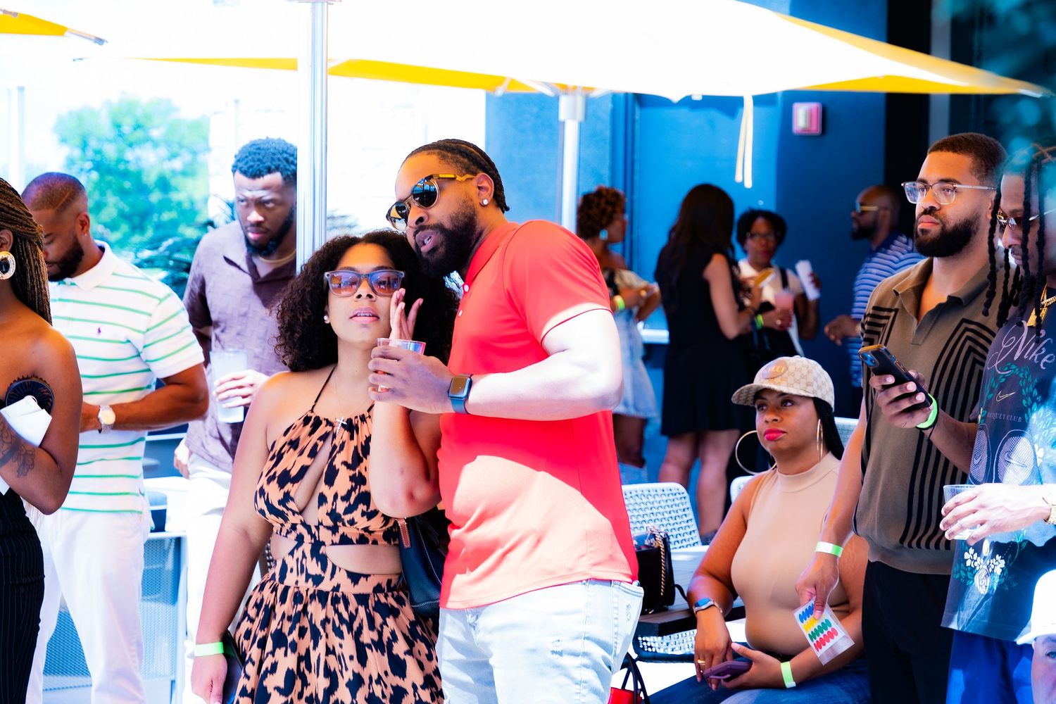 Attendees mingling under a white tent at an outdoor social gathering.