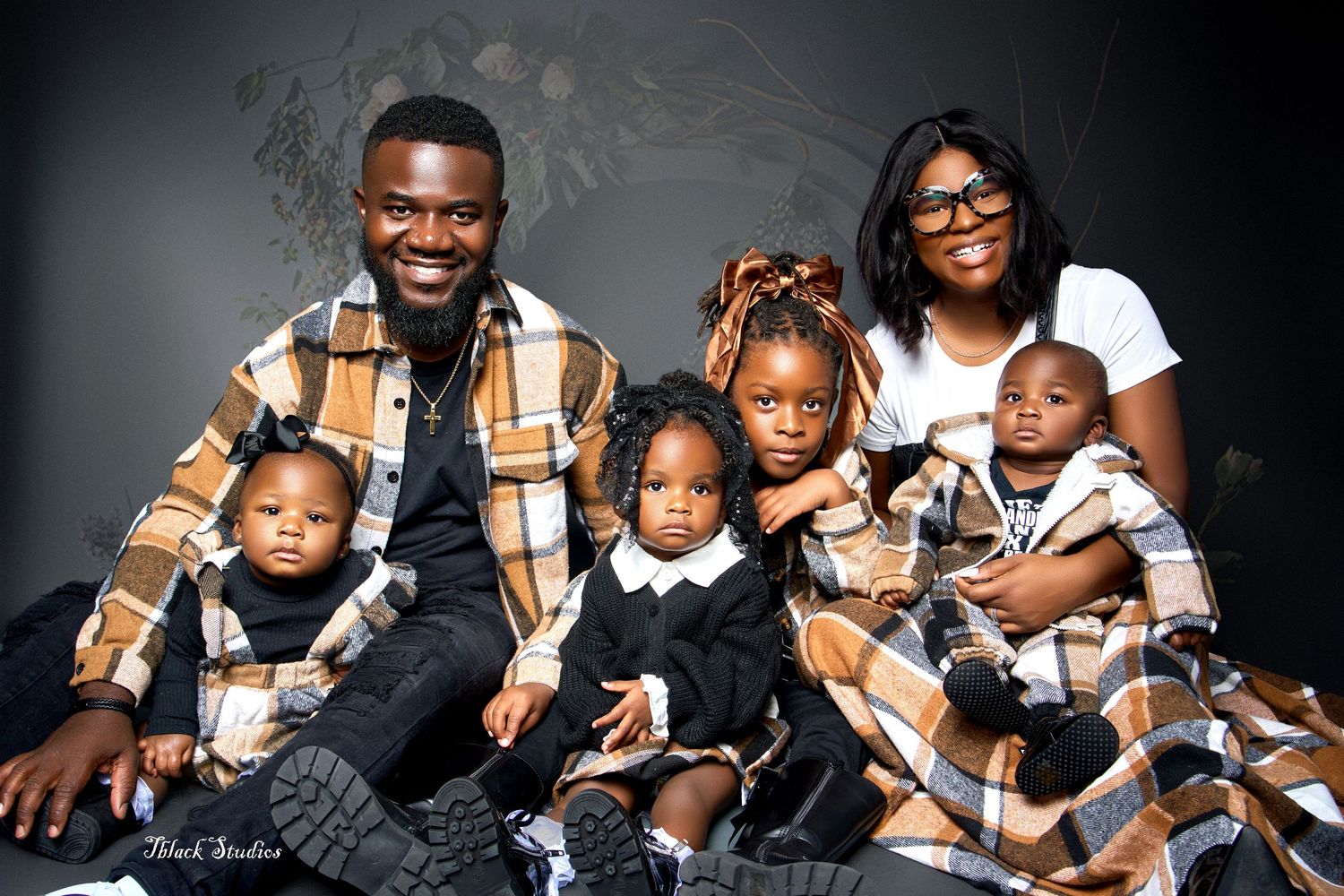 Modern family portrait series with coordinated black and brown outfits against dark background.
