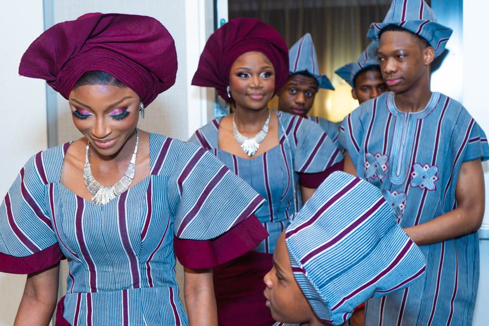 Guests wearing coordinated blue and burgundy traditional African print outfits at an event.