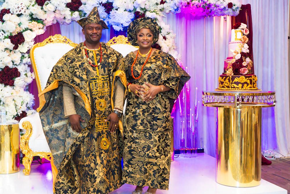 Traditional African wedding celebration with colorful attire and floral decorations at an elegant indoor venue.
