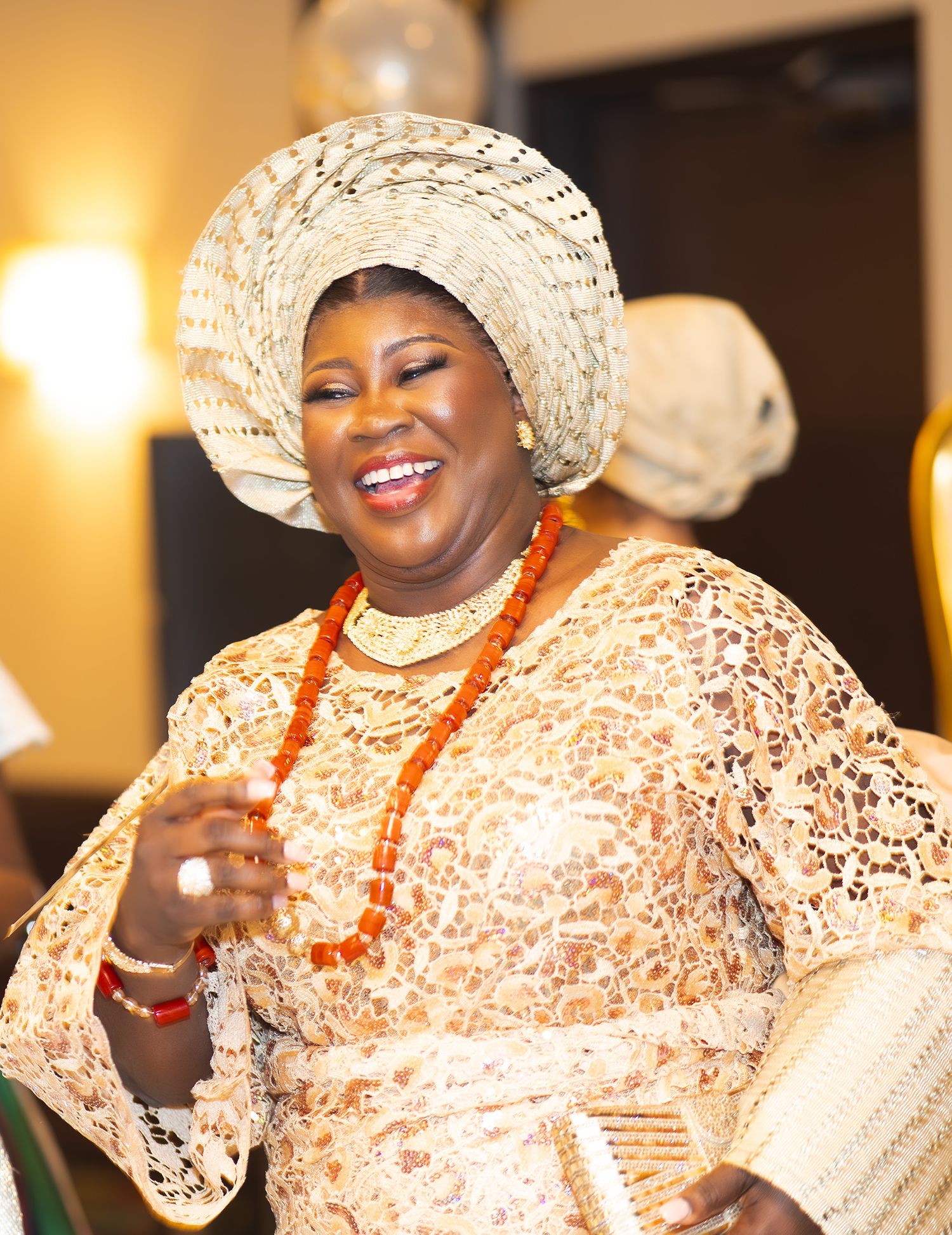 Joyful celebration with attendees wearing matching cream lace outfits and traditional white gele headwraps.