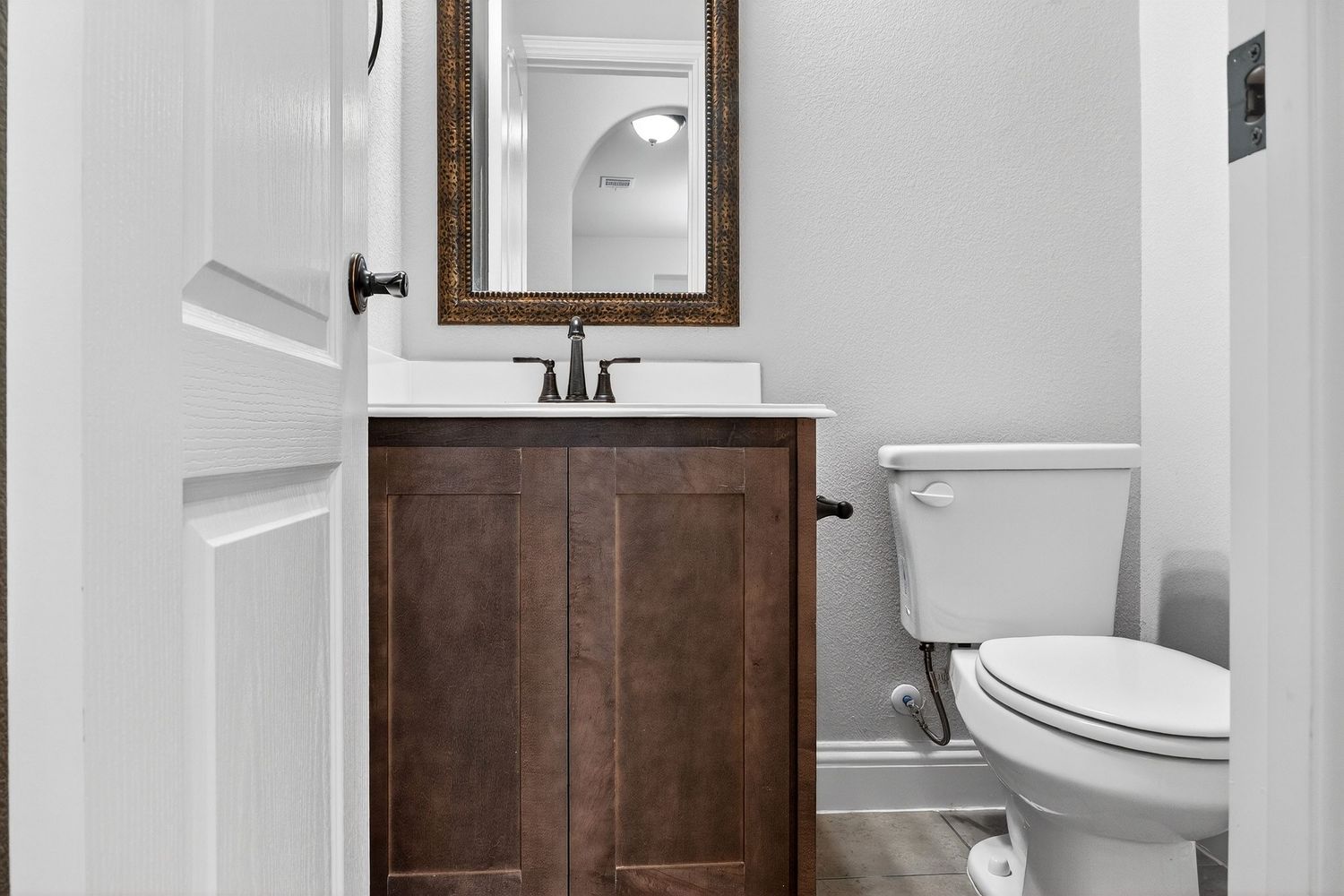 Modern bathroom with brown tile accent wall, white fixtures, and framed mirror above vanity.