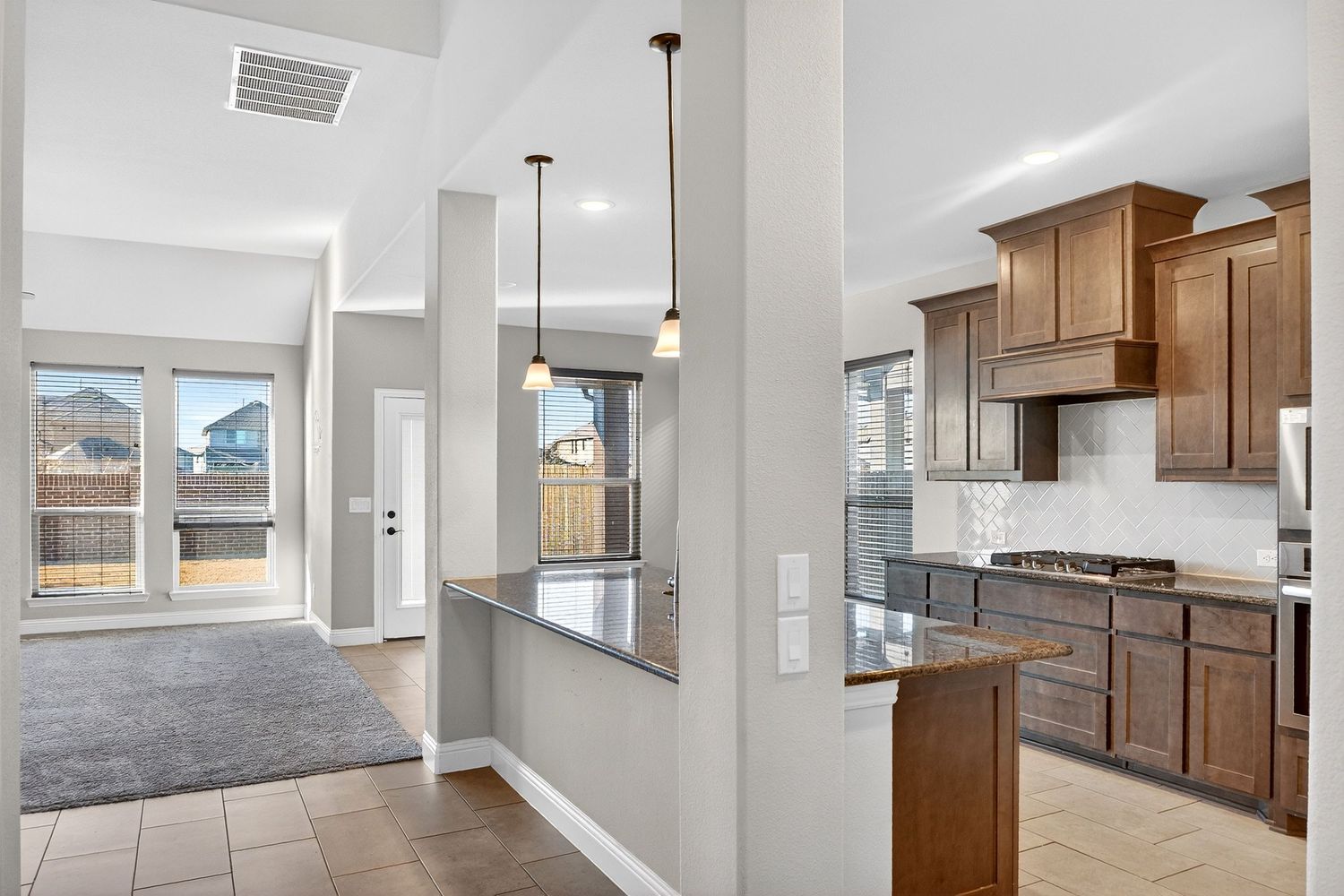 Open concept living space with high ceilings, wood cabinets, and large windows providing natural light.