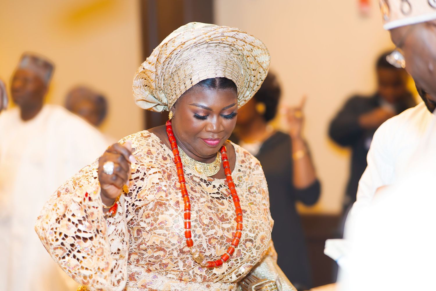 Nigerian wedding guests in traditional cream and white attire dancing during celebration.