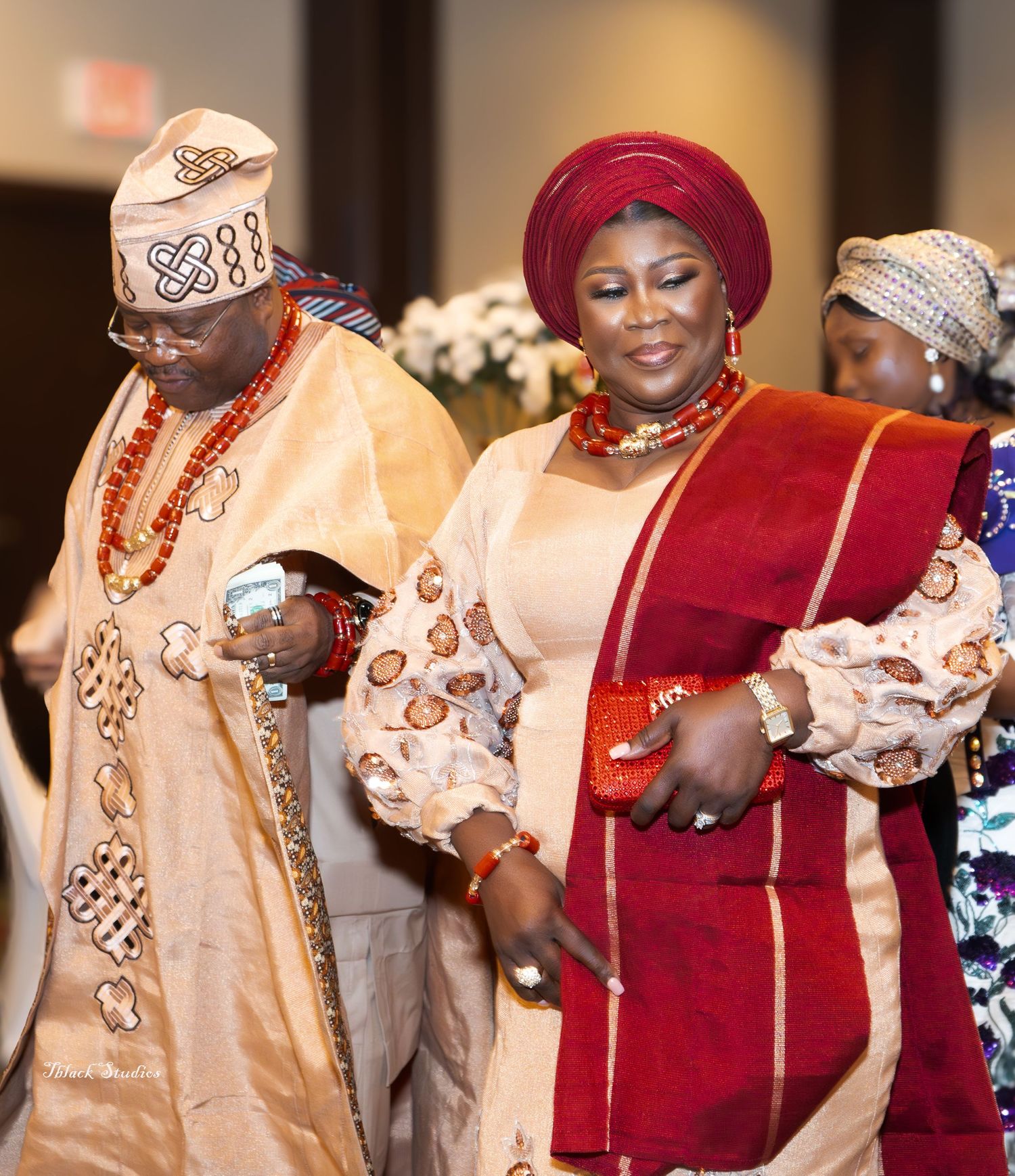 Guests in traditional Nigerian clothing and geles celebrating at an elegant indoor event.
