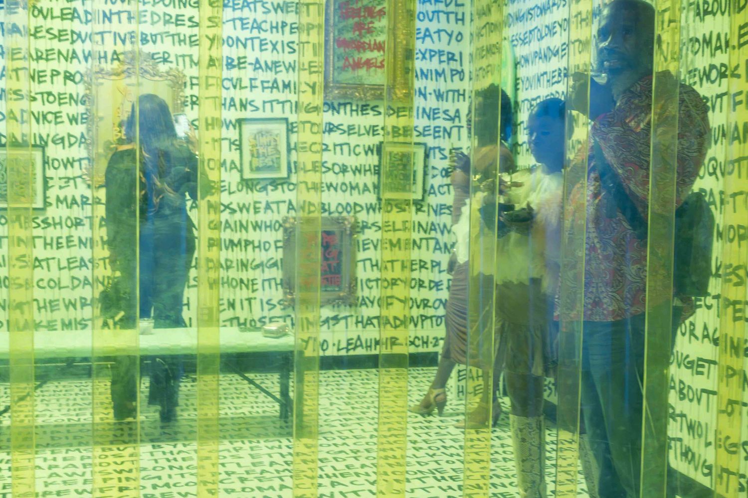 Green-tinted gallery space with text overlays and reflective surfaces.