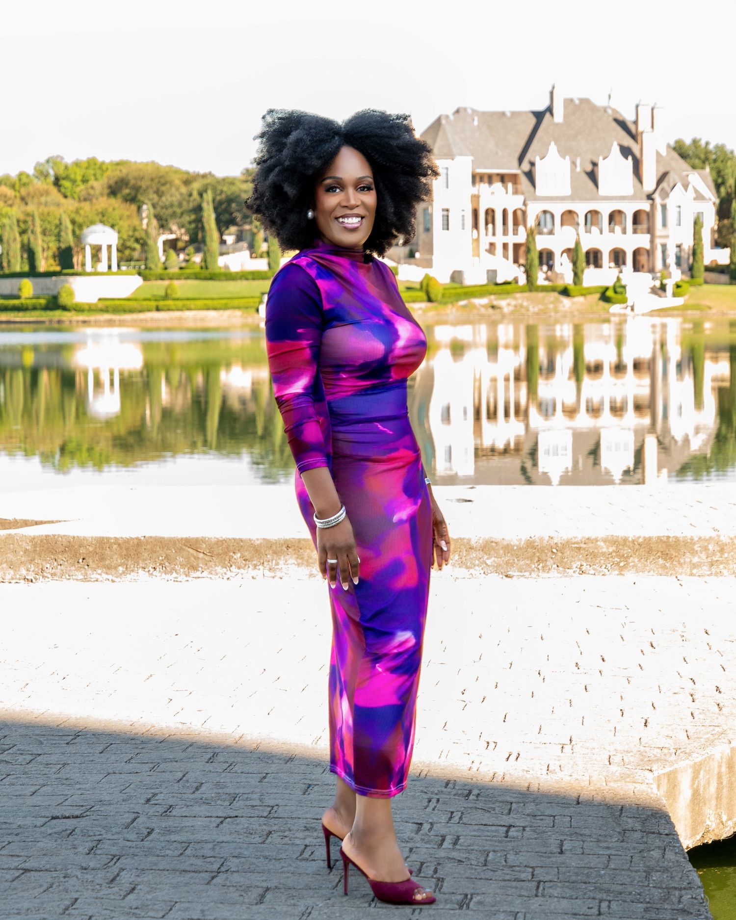 Fashion photography by a lakeside featuring a bold purple and pink patterned dress.