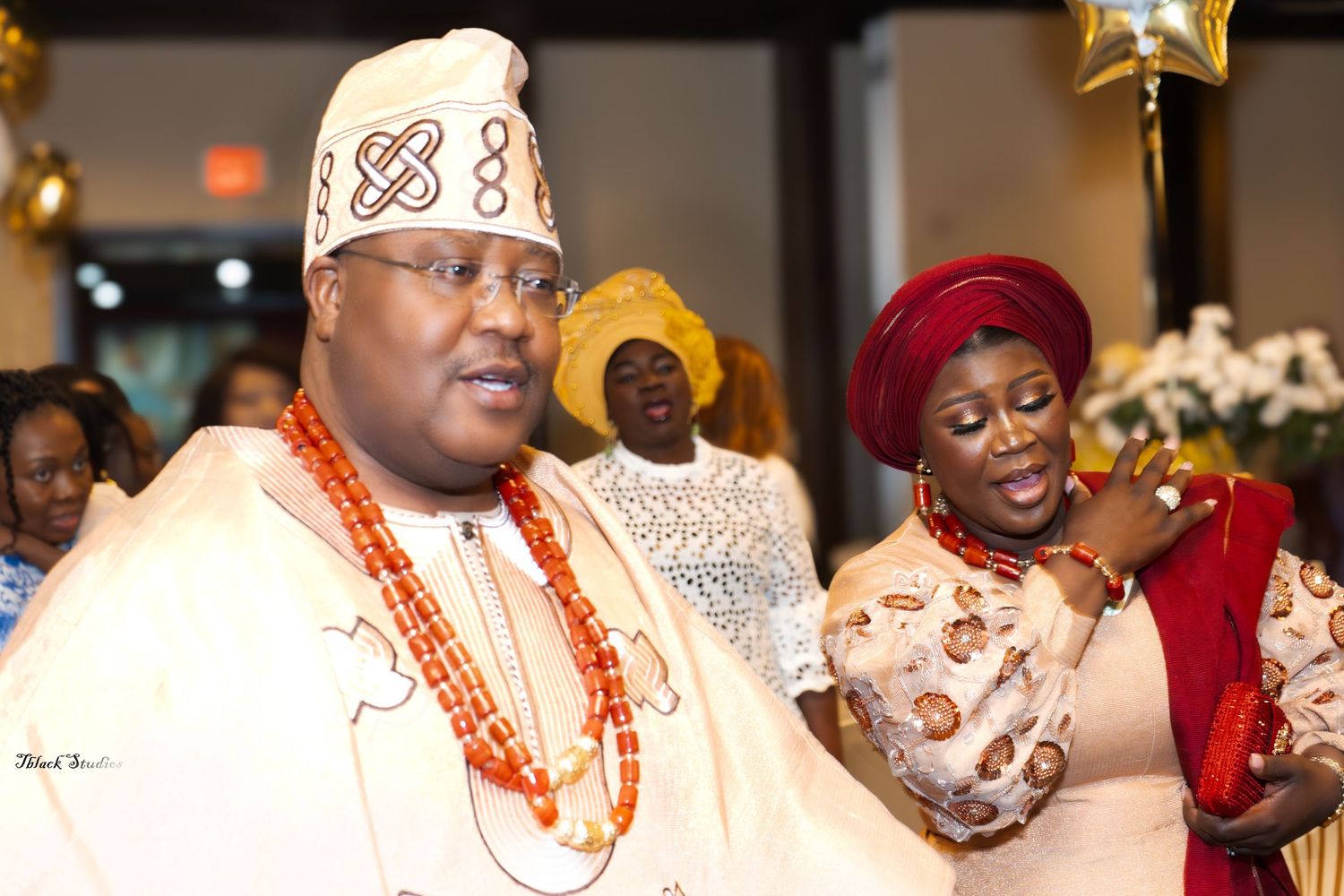 Celebratory gathering showing people in traditional West African formal wear dancing and socializing.