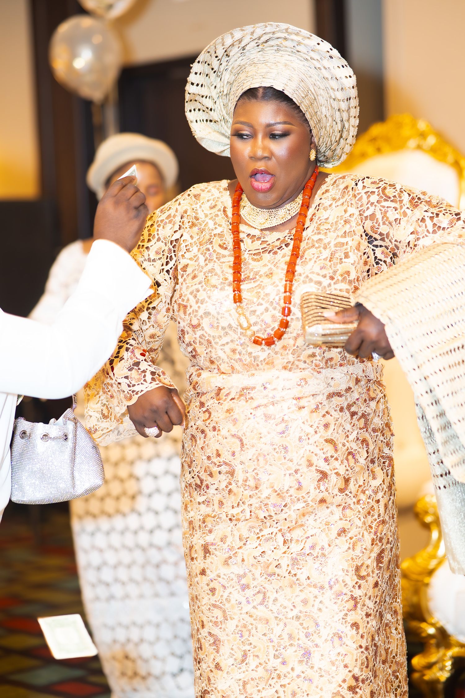 Wedding celebration showing dancers in coordinated cream lace attire and traditional coral beaded necklaces.