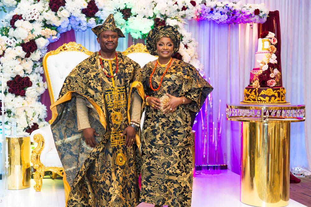 Wedding party members in vibrant gold and black traditional African formal wear posing together.