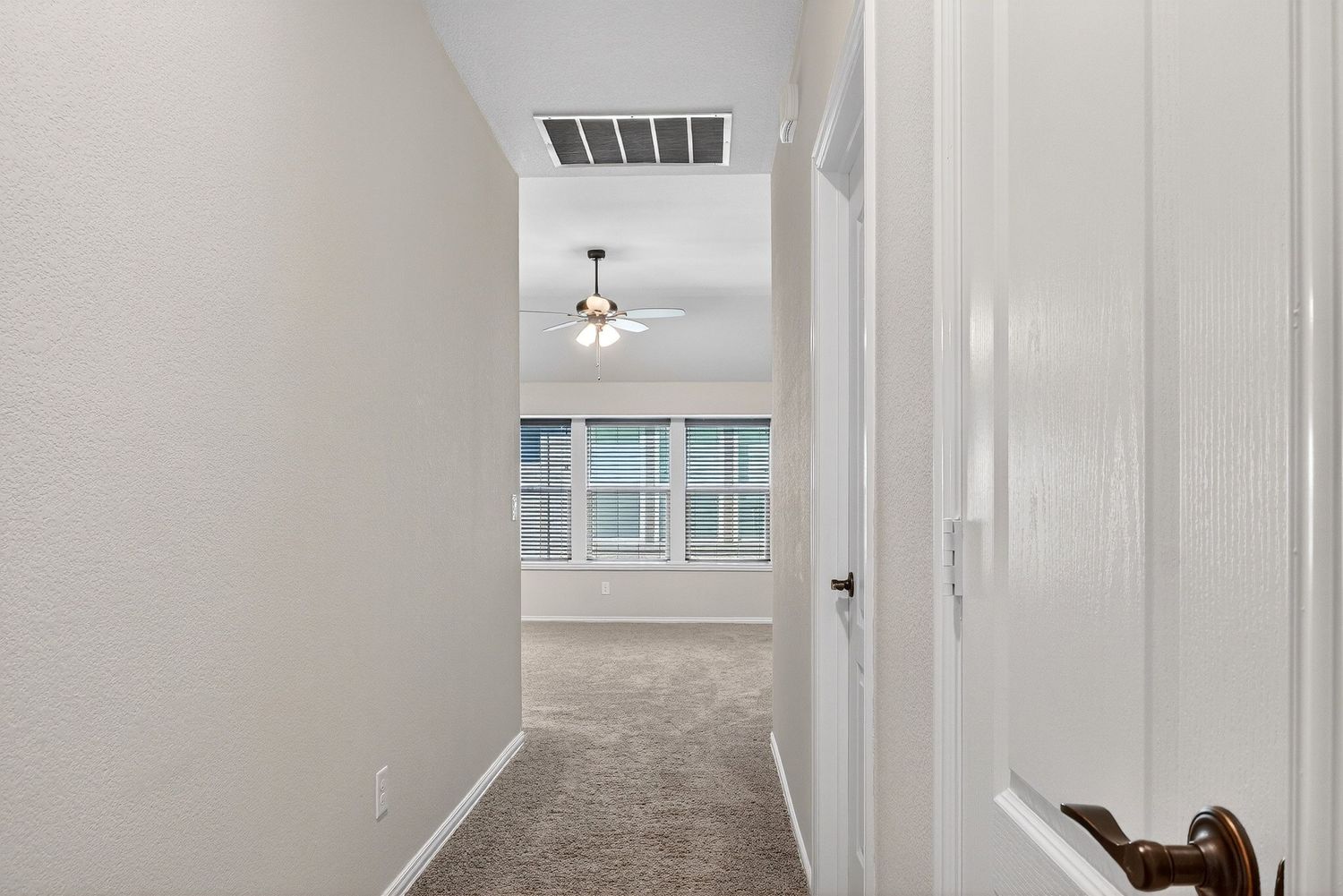 Upstairs hallway with white walls, ceiling light fixture, and carpeted flooring.