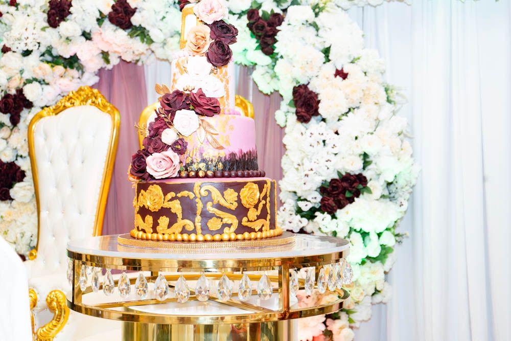 Elegant event decor featuring white and burgundy floral arrangements with golden accents.