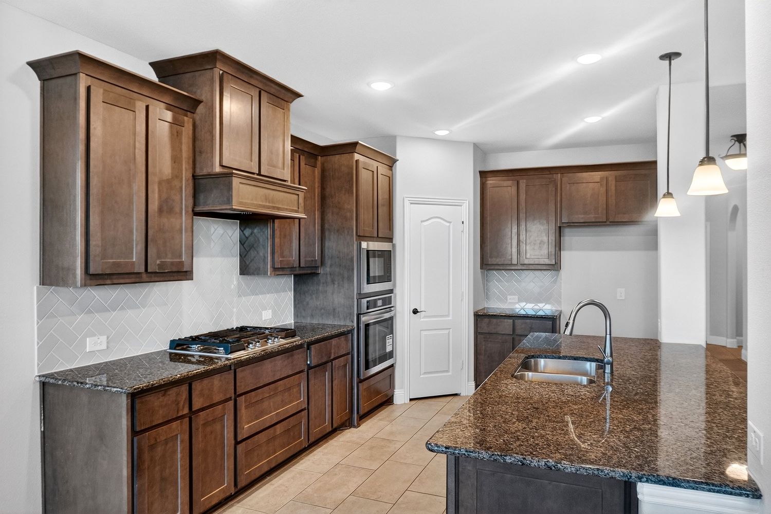 Modern kitchen with dark wood cabinets, granite countertops, and stainless steel appliances in an open layout design.