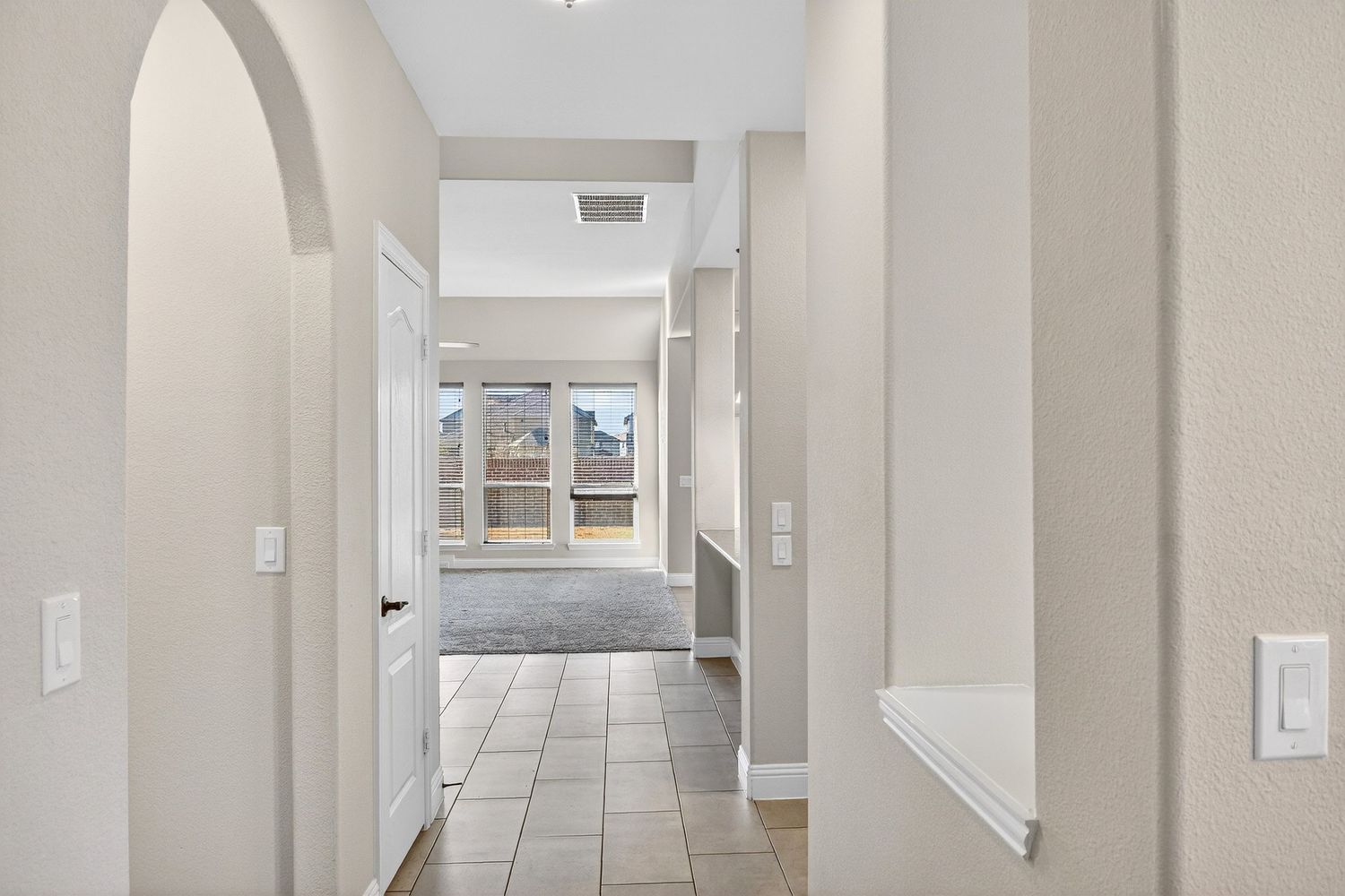 Long bright corridor with white walls and recessed lighting leading to multiple doorways.