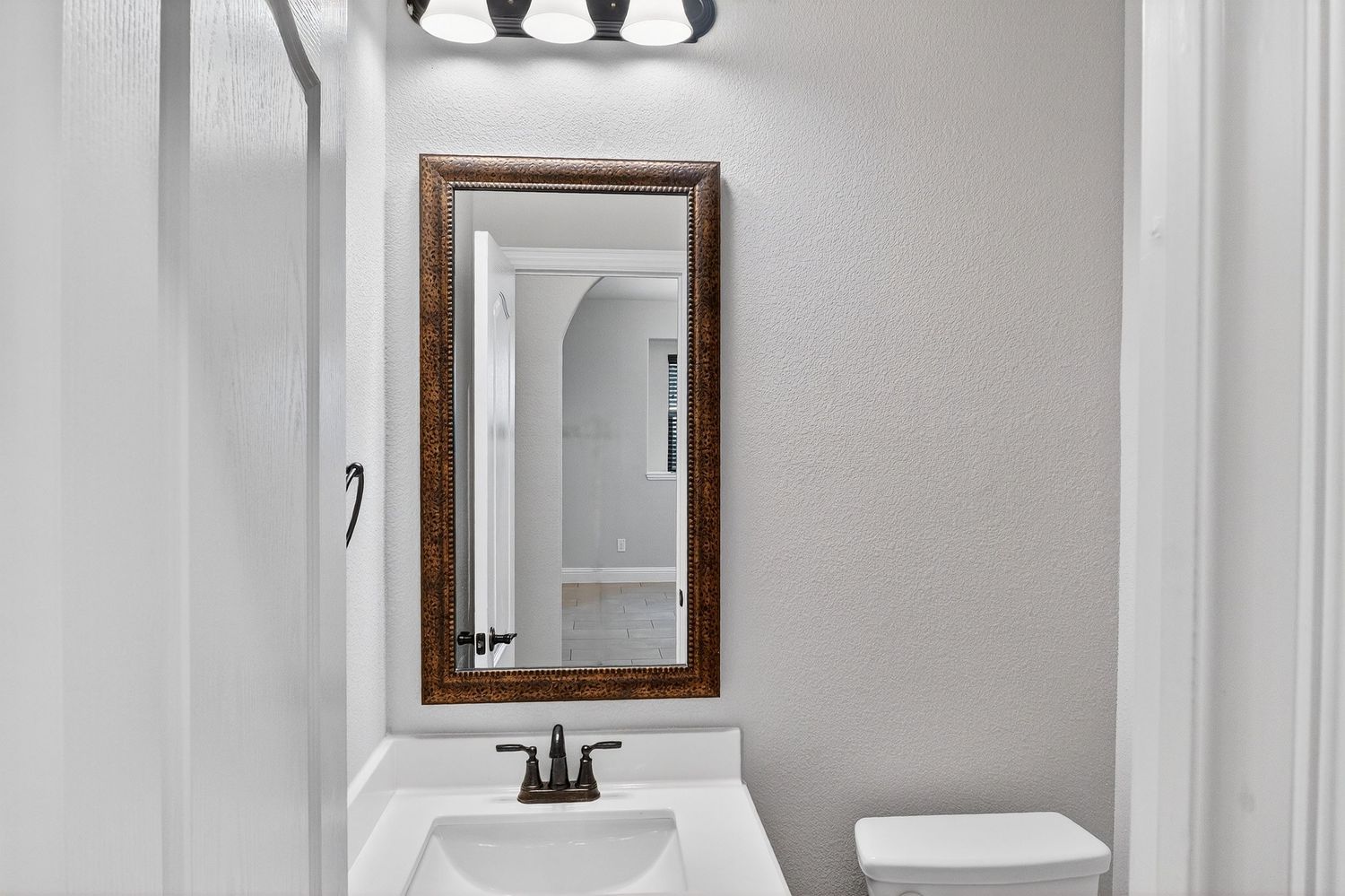 Bright white hallway with wood-framed mirror and contemporary light fixtures mounted on walls.