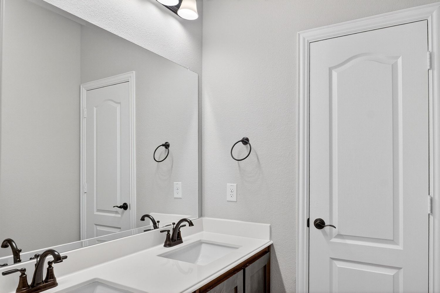Modern bathroom with white vanity, bronze fixtures, and panel doors.