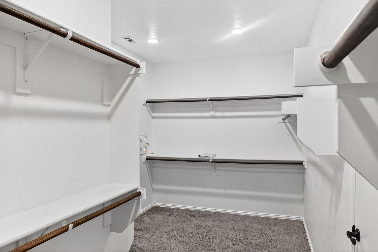 White painted utility room with exposed pipes and mechanical systems on the ceiling.