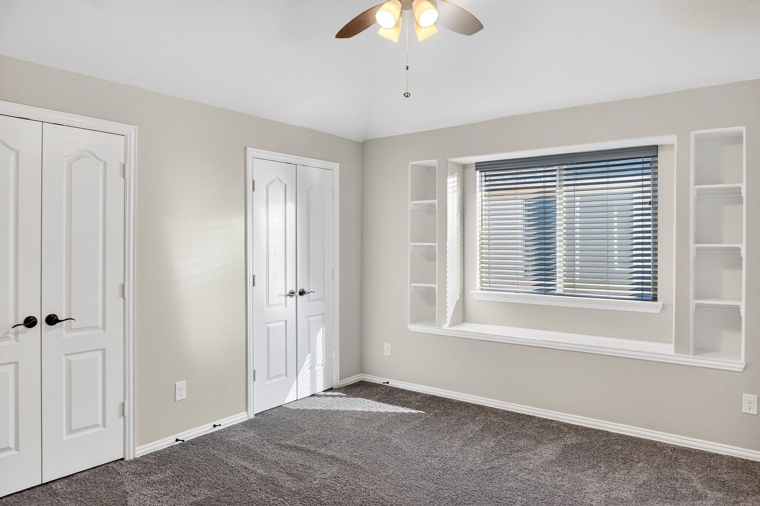Large living area with ceiling fan, multiple windows, and neutral paint colors throughout.