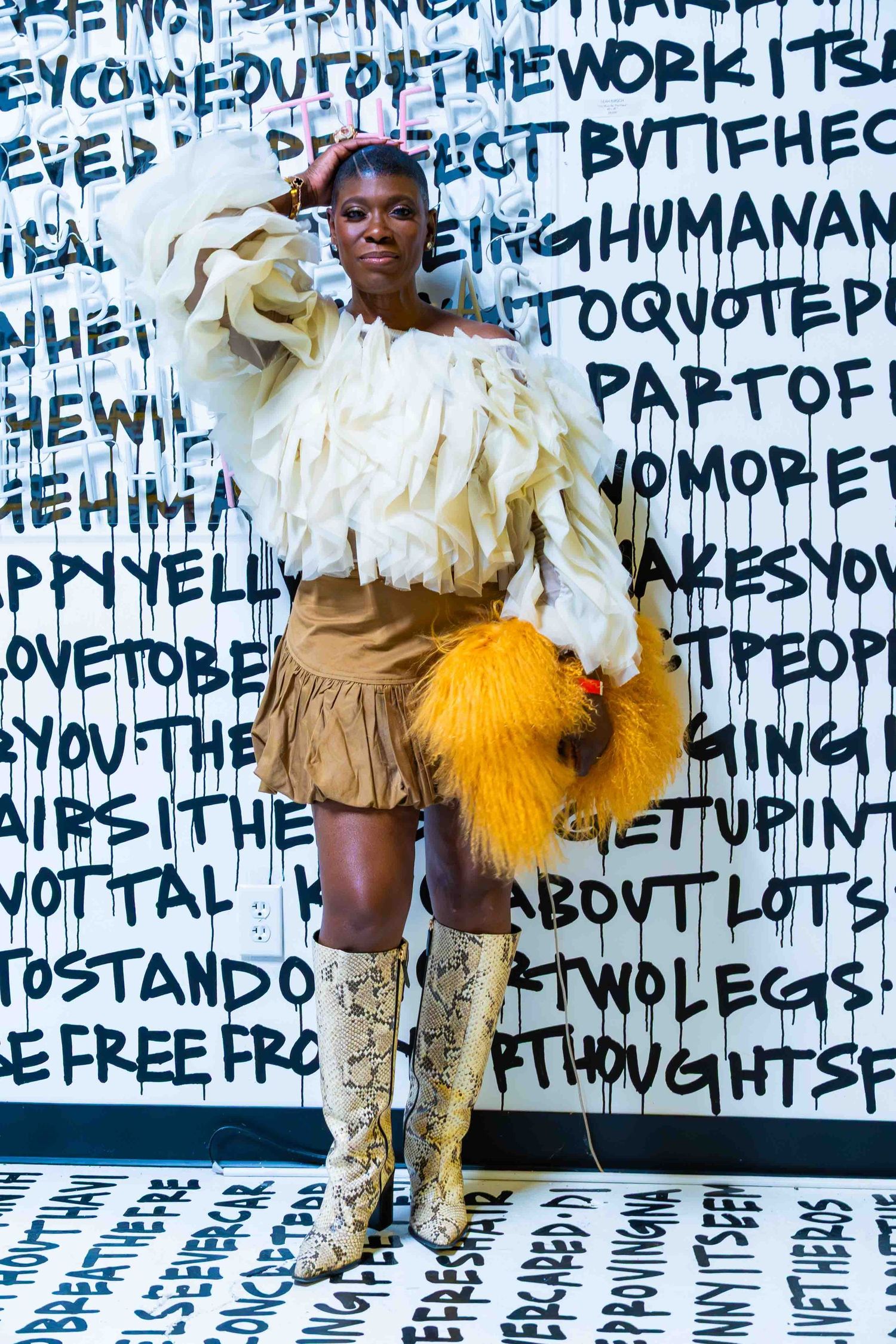 Dramatic costume featuring cream and yellow ruffles against text-covered backdrop.