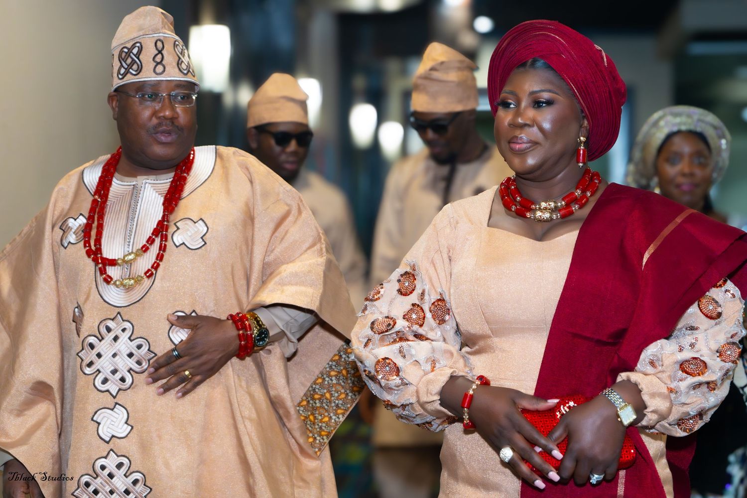 Nigerian wedding reception with guests wearing coordinated traditional outfits and headwear.