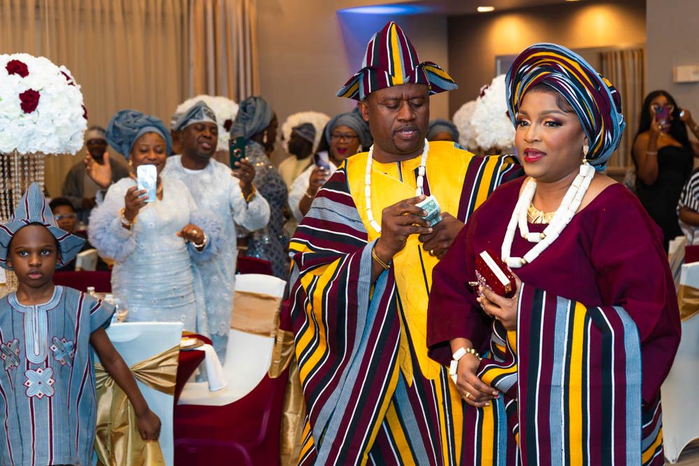 Wedding celebration featuring attendees in colorful traditional African attire with striped patterns.