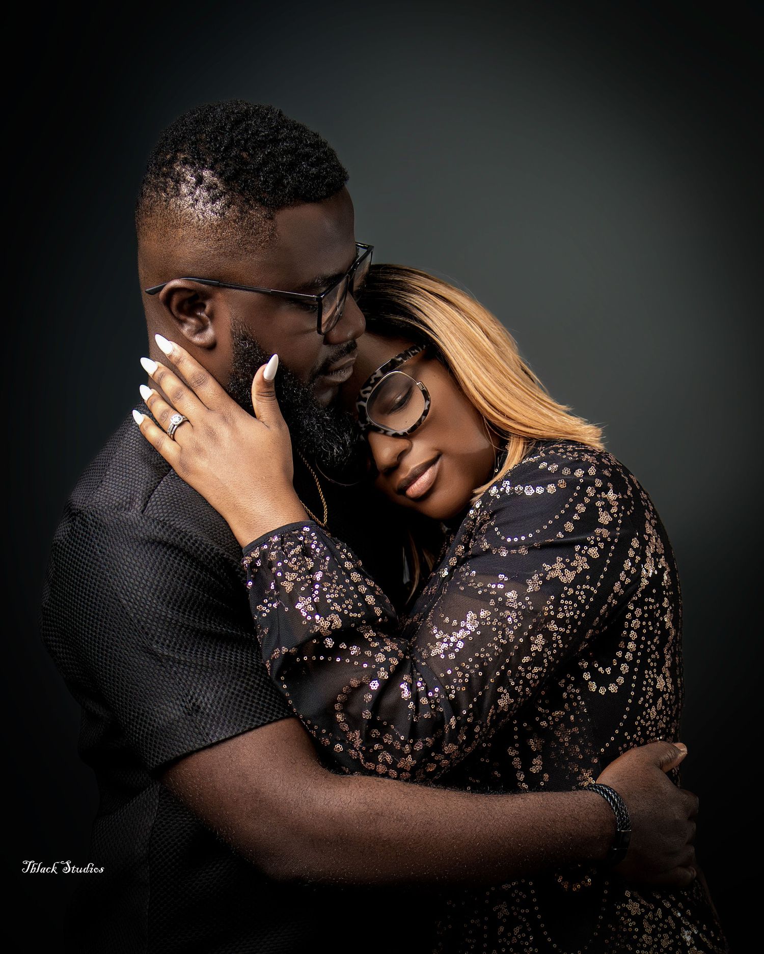 Intimate portrait of couple embracing in dark setting wearing formal attire.