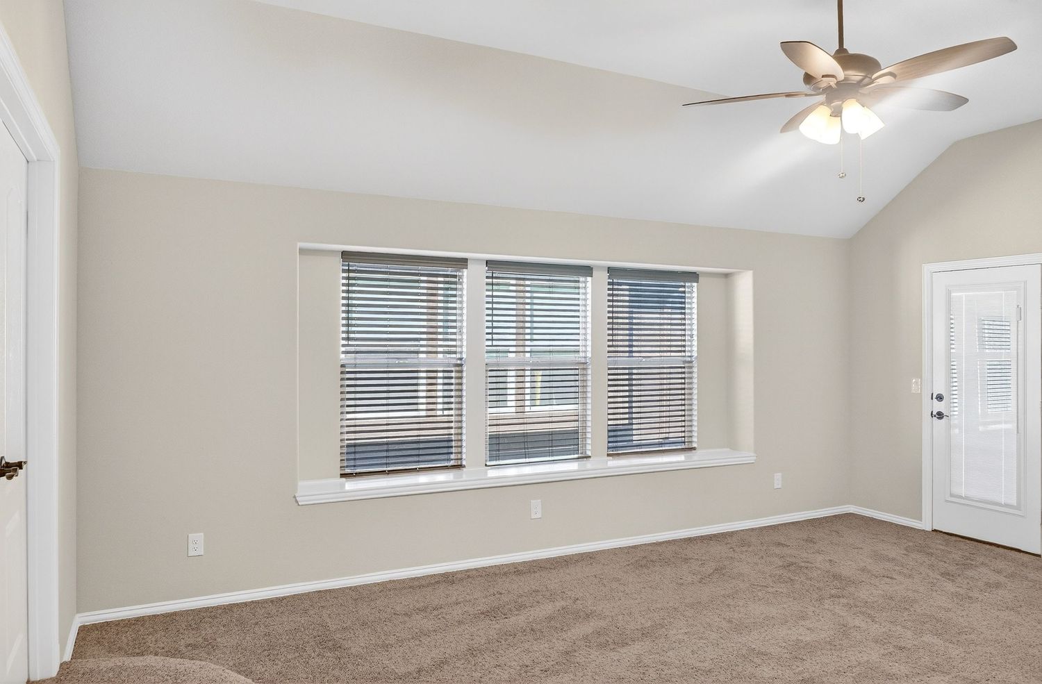 Large carpeted room with high ceilings and multiple windows providing natural light.