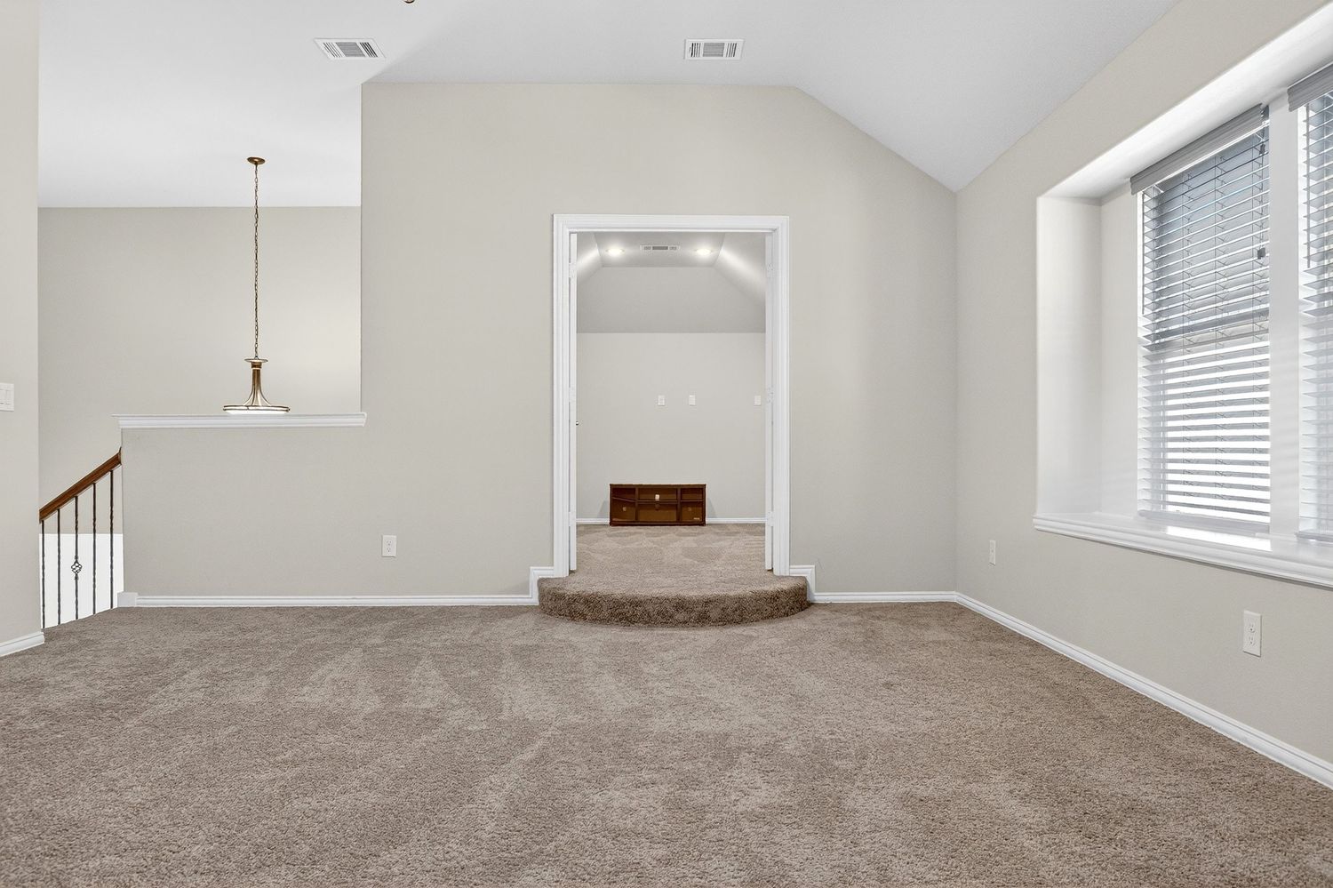 Expansive living space with cathedral ceiling, carpet flooring, and arched doorway.