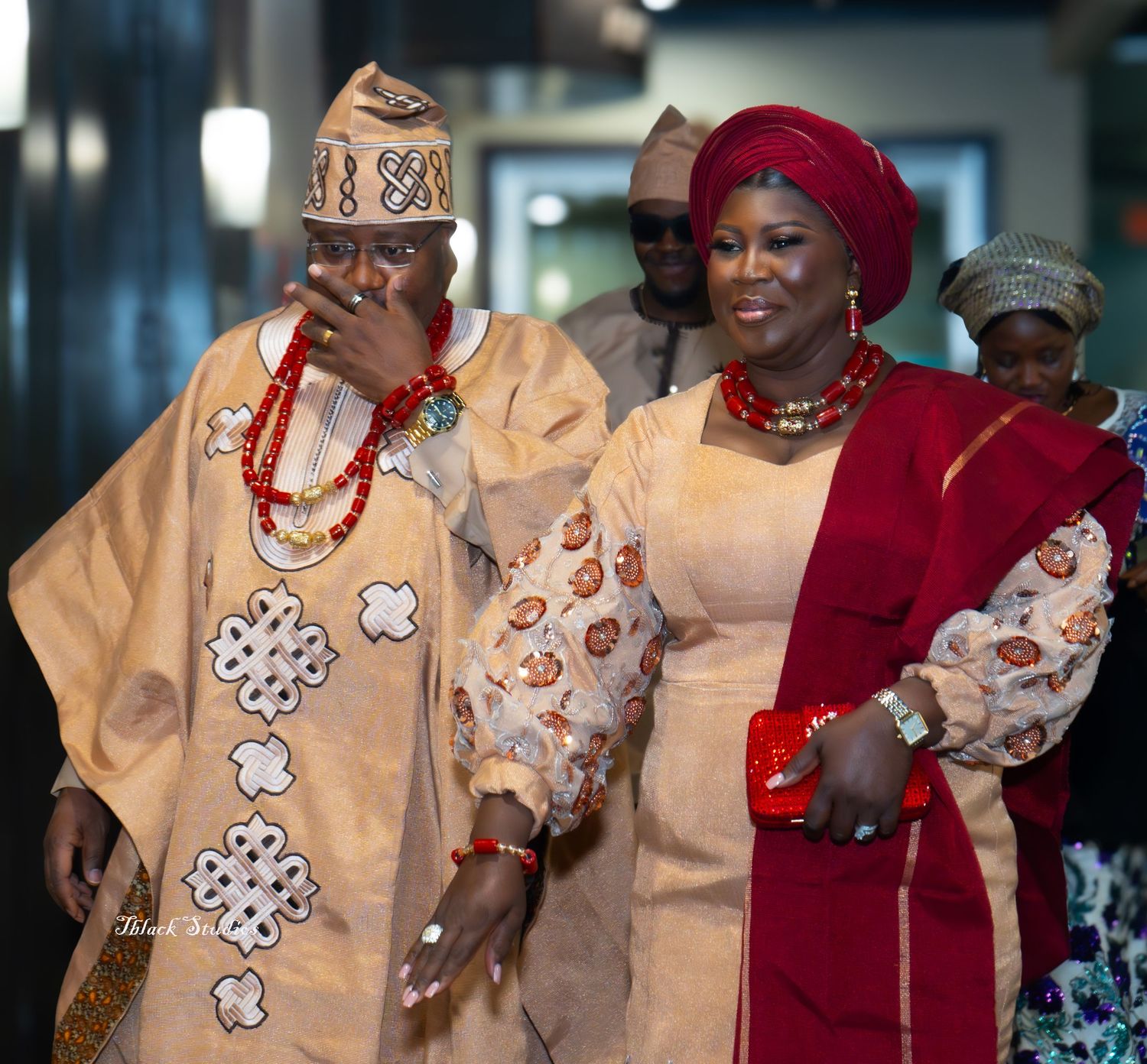 Traditional Nigerian wedding celebration featuring vibrant red and cream colored formal attire and cultural accessories.