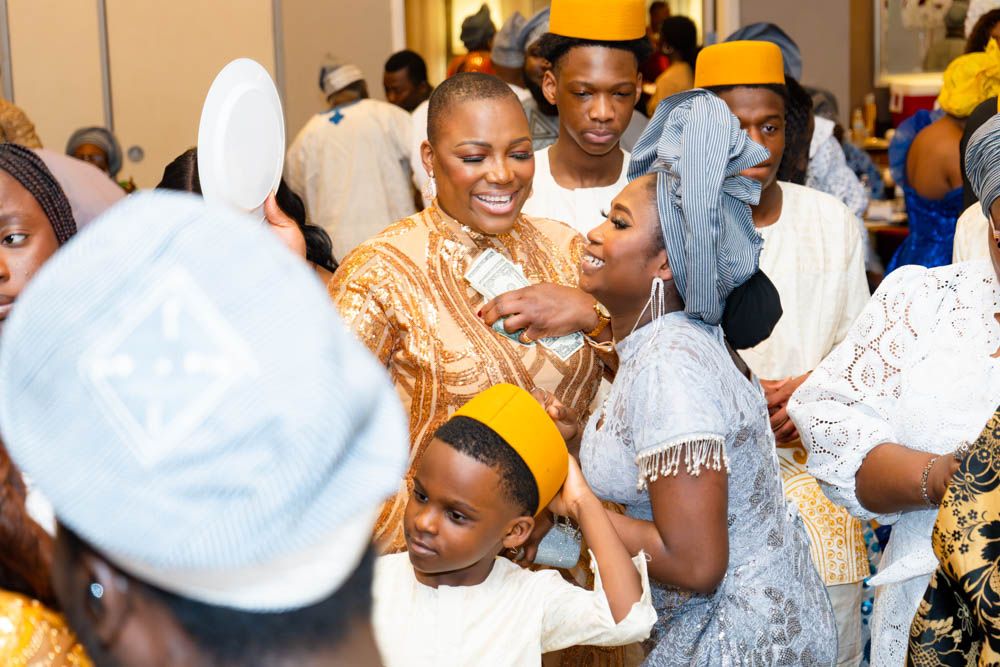 Wedding guests mingling and celebrating in traditional African dress at indoor venue.