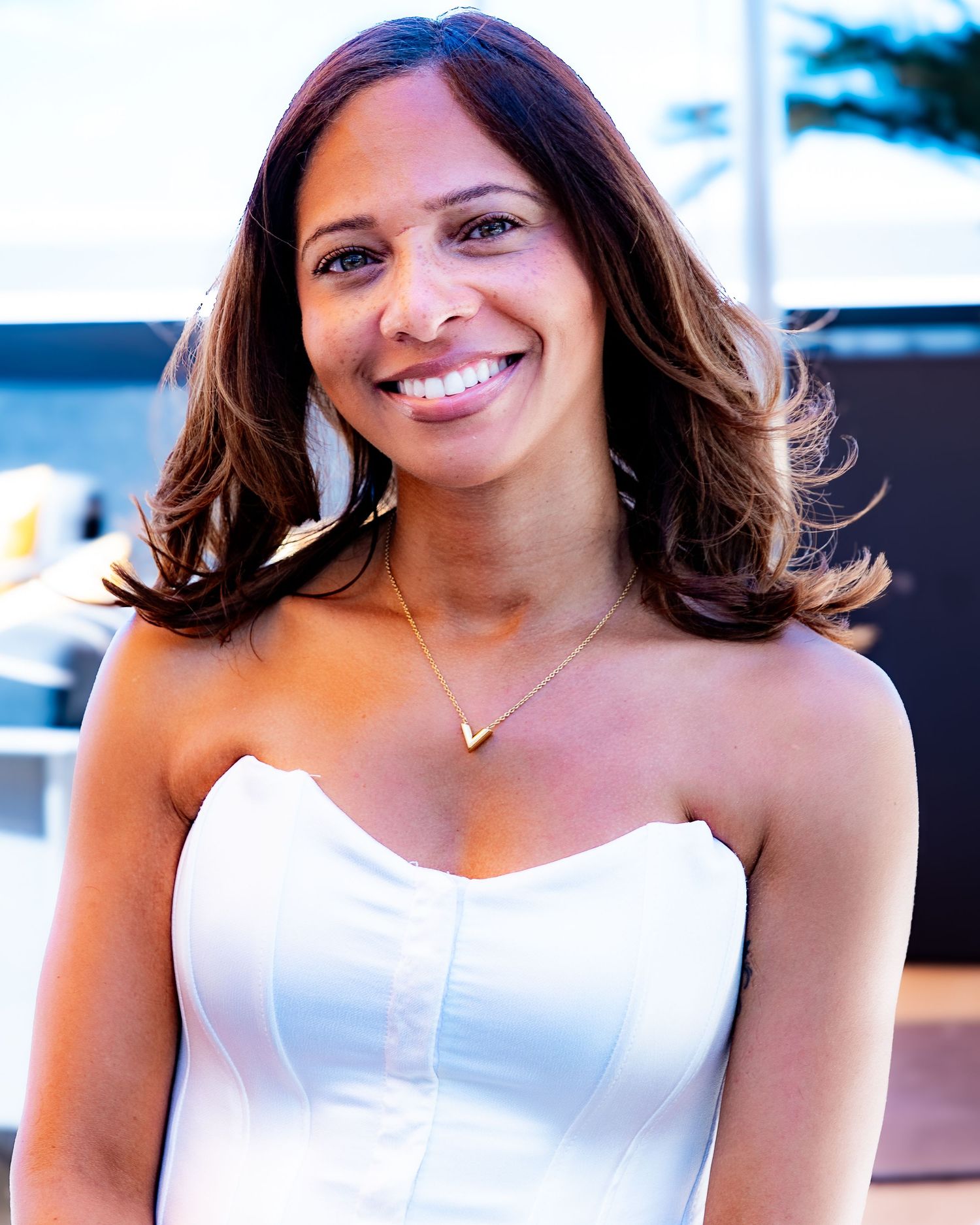 Portrait of woman in white strapless dress with radiant smile.