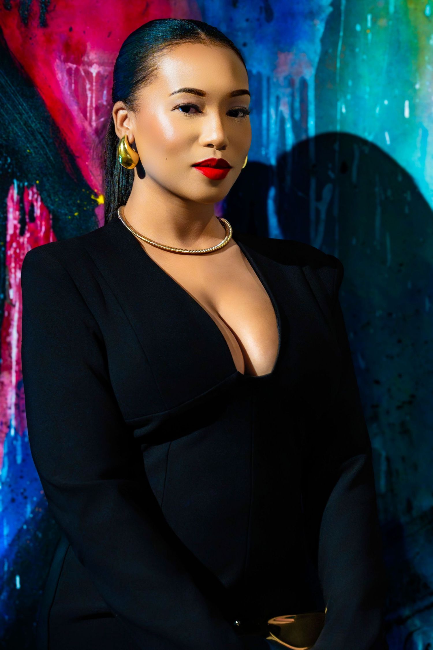 Fashion photography featuring elegant black attire against vibrant painted wall backdrop.