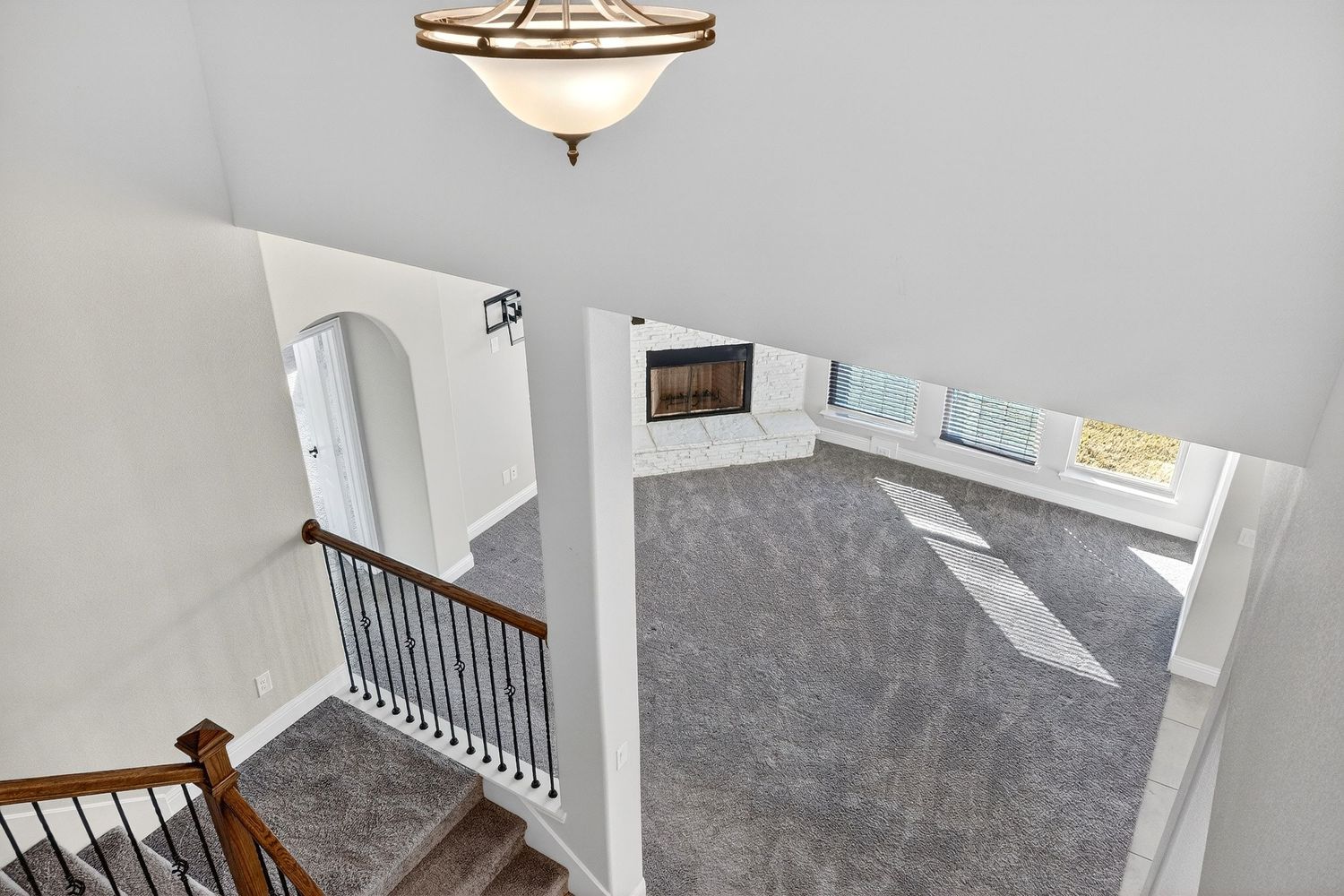 View down carpeted staircase with wooden handrails and white walls.