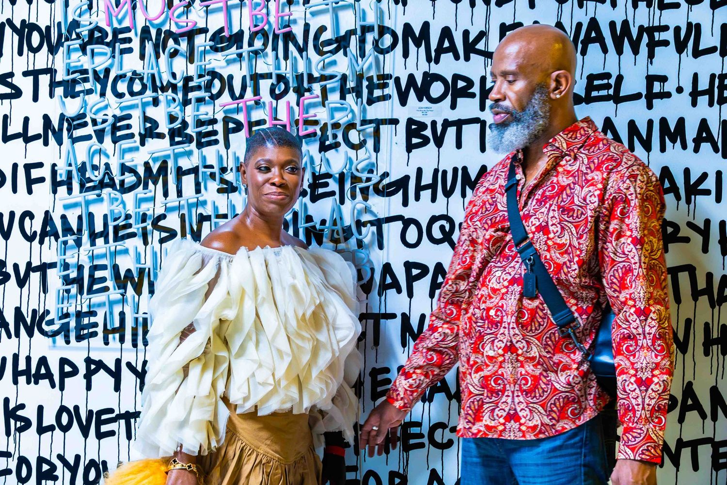Art installation with text-covered walls featuring performers in colorful outfits.
