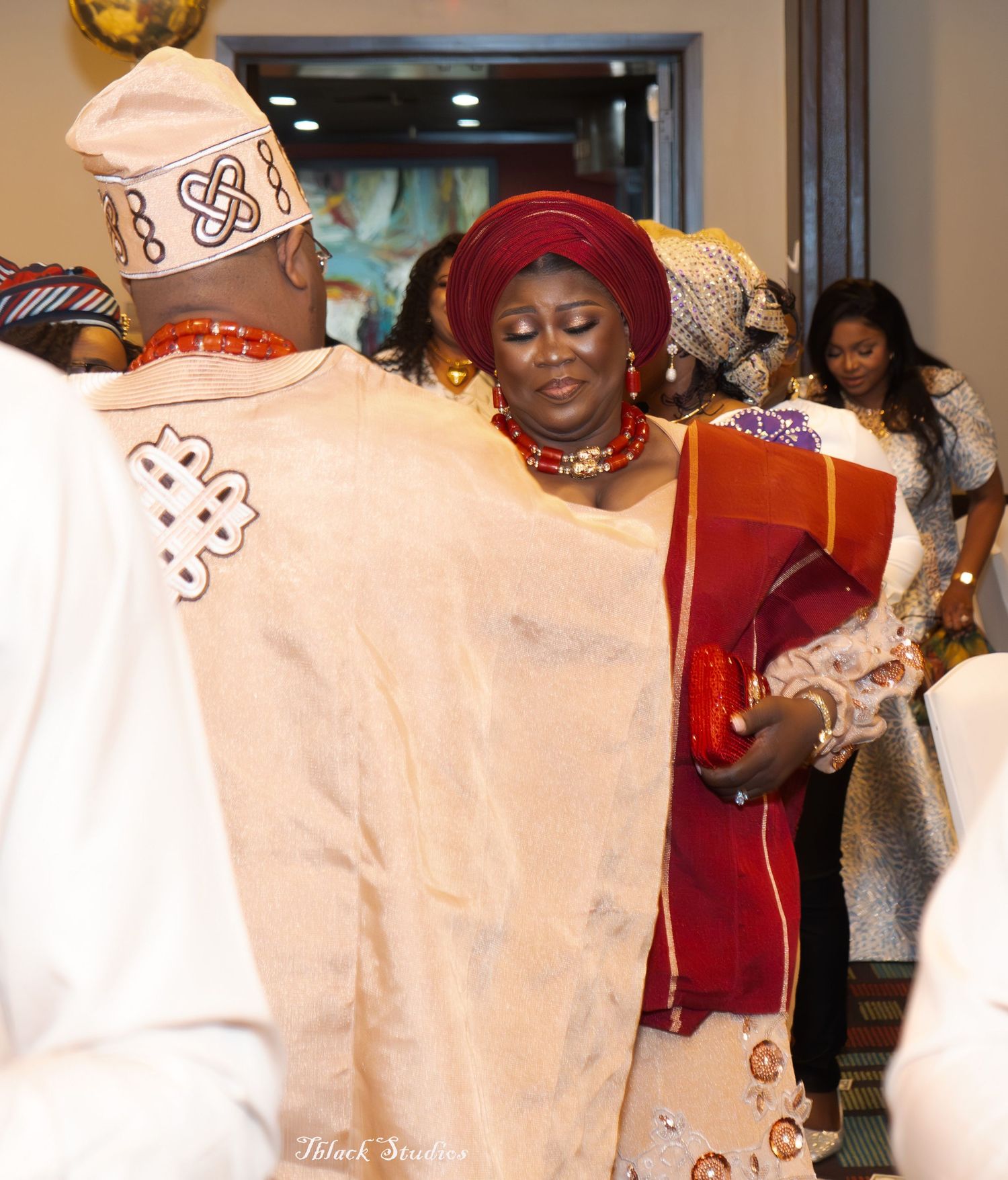 Wedding celebration showing attendees in cream-colored traditional African attire with decorative patterns.