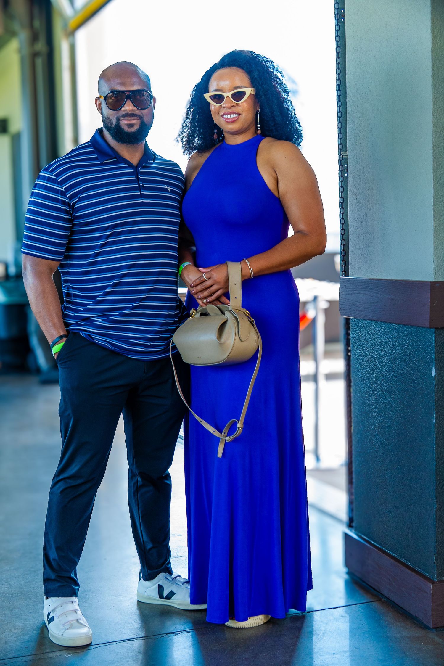 Stylish couple in blue outfits posing at an outdoor venue.