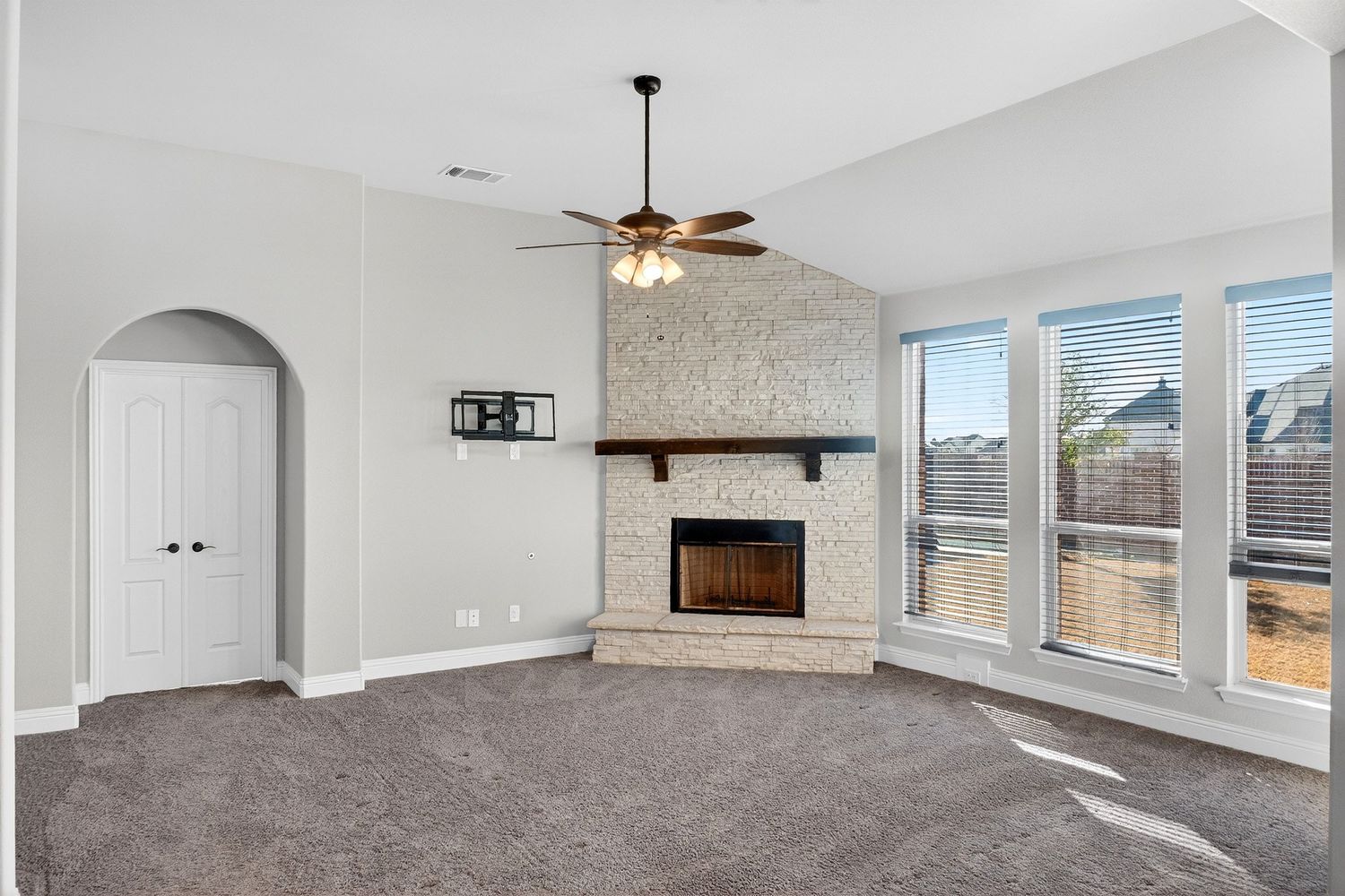 Open concept living area with vaulted ceilings, large windows, and beige carpeting.