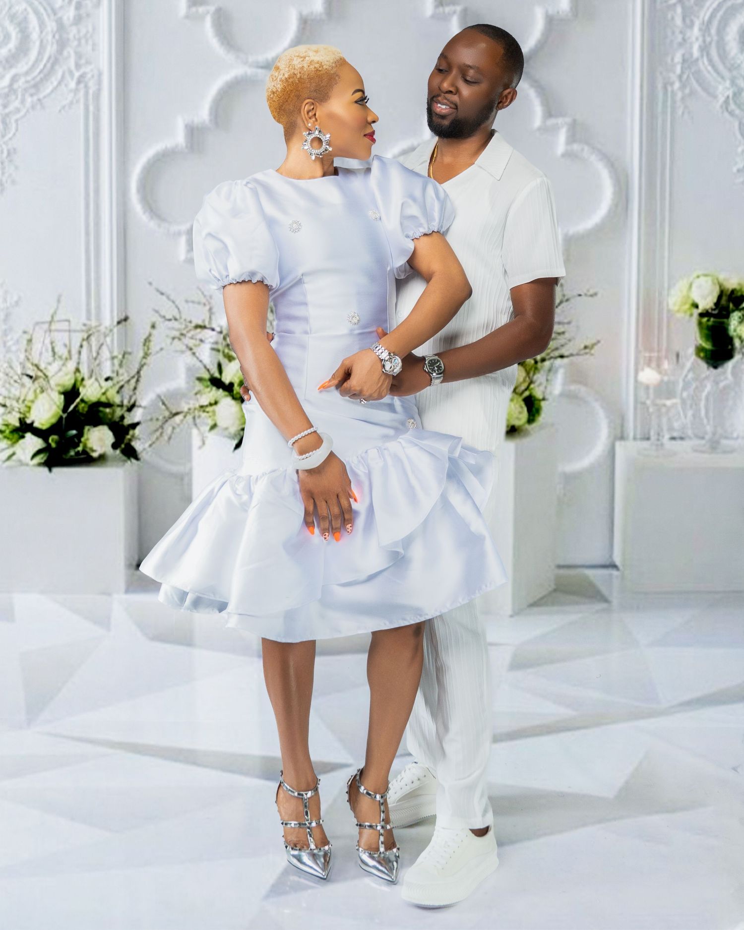 Romantic photoshoot in all-white room with ornate molding and floral decorations.